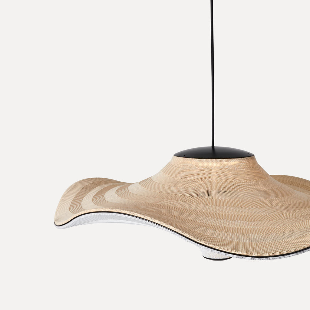 Made by Hand Flying Ø96 Pendant Lamp, a large organic modern pendant lamp featuring a wide, wavy shade crafted from a finely woven beige textile with subtle horizontal stripe variations. Its undulating silhouette, black metal canopy, and contrasting silver interior create a striking contemporary design. Ideal as a statement ceiling light for minimalist living rooms, dining areas, or spacious entryways.