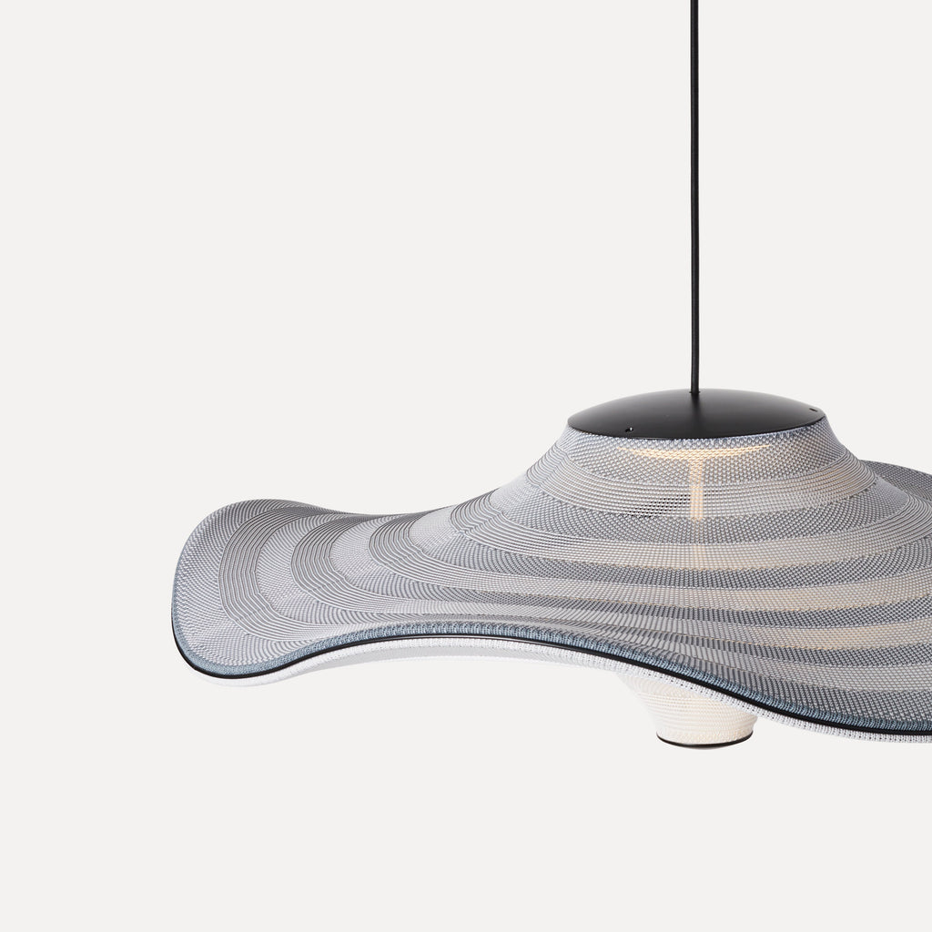 Made by Hand Flying Ø96 Pendant Lamp, a large organic modern pendant light featuring a wide, wavy shade crafted from woven grey and off-white textile with subtle blue edge details and a matte black metal canopy. This contemporary ceiling lamp offers a soft, diffused glow, creating an inviting ambiance. Perfect for Scandinavian living rooms, minimalist dining areas, or spacious entryways seeking a statement piece.