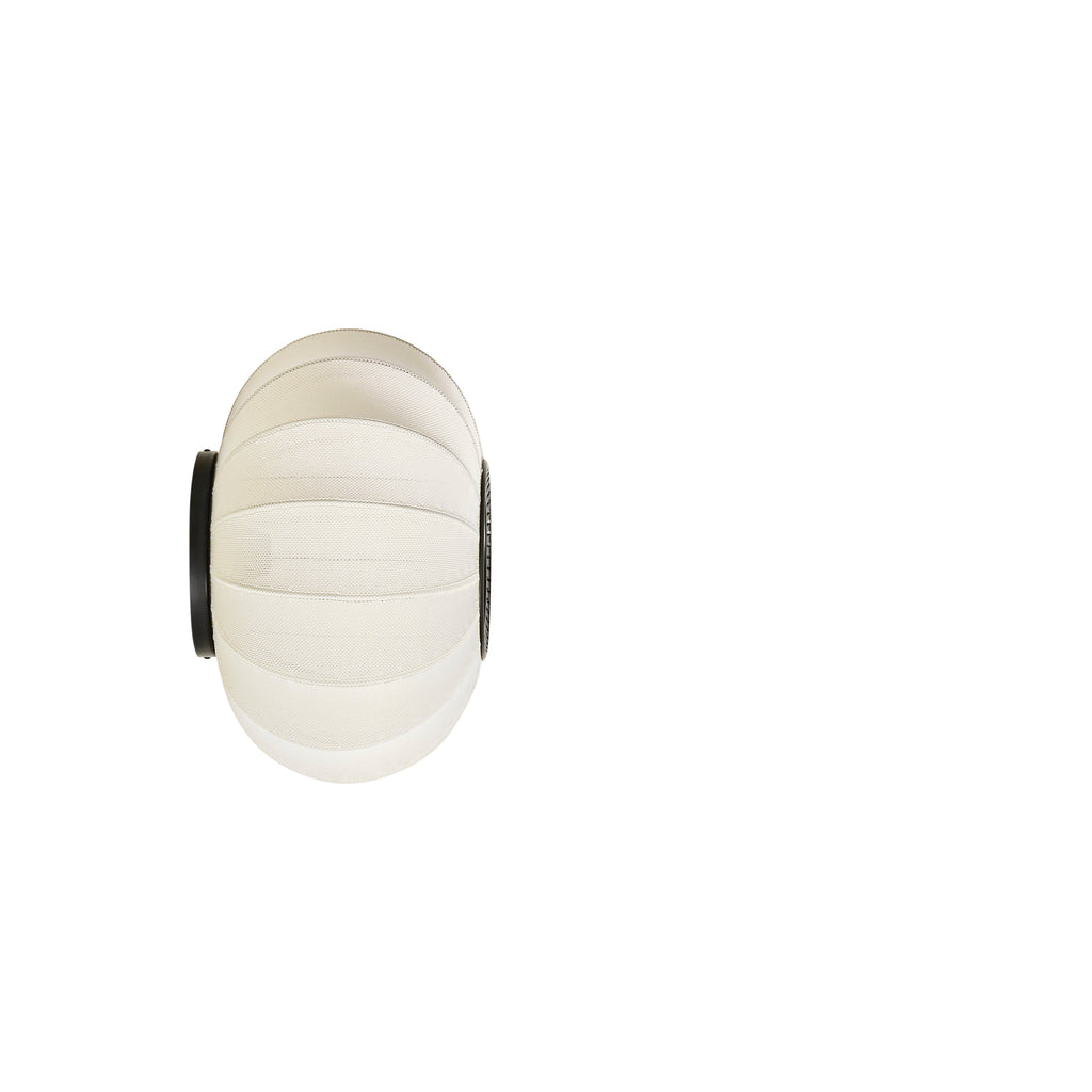 Made by Hand Knit-Wit Ø45 Oval Wall Light, a modern Scandinavian wall lamp featuring a unique oval, globe-like shade crafted from hand-knitted cream textile with distinct horizontal woven bands. This contemporary fabric wall light offers soft diffused illumination, mounted with sleek matte black metal hardware, ideal for adding an organic modern touch to living rooms, bedrooms, or hallways.