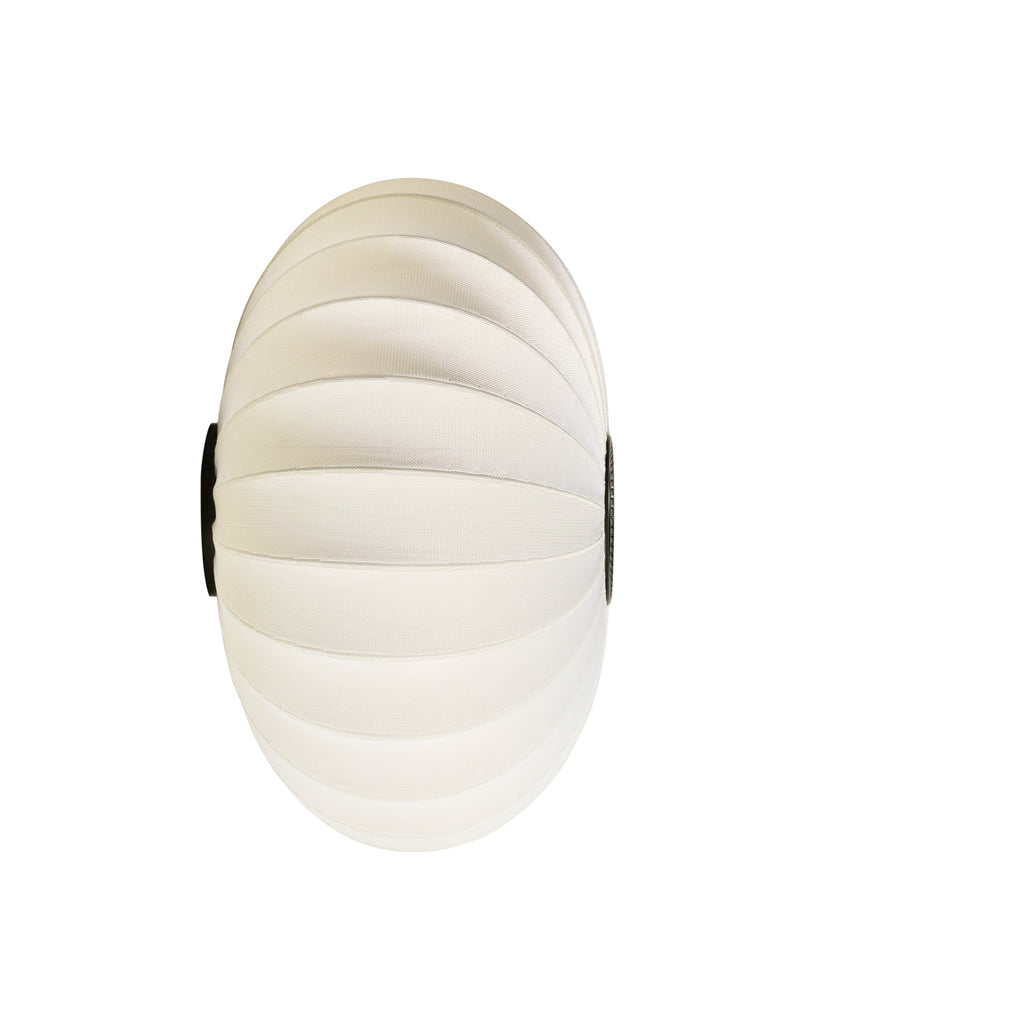 Made by Hand Knit-Wit Ø76 Oval Wall Light, a contemporary Scandinavian wall lamp crafted from a unique knitted polyester yarn in a soft cream color, forming an elegant oval globe shape with a subtle ribbed texture. This designer wall light provides warm, diffused ambient lighting, perfect for minimalist living rooms, modern bedrooms, or elegant hallways.