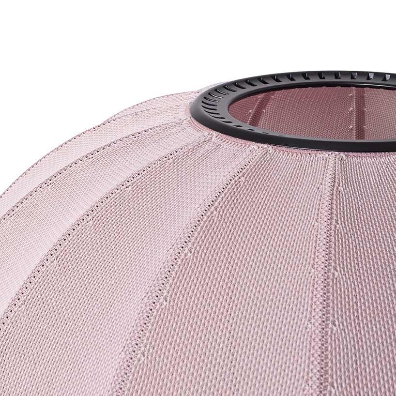 Made by Hand Knit-Wit Ø57 Oval Wall Light, a modern Scandinavian wall lamp featuring a soft dusty pink knitted textile shade with a distinct ribbed texture and a sleek black metal top ring. This spherical fabric light fixture offers warm, ambient illumination, perfect for creating a cozy atmosphere in minimalist living rooms, contemporary bedrooms, or organic modern nurseries.