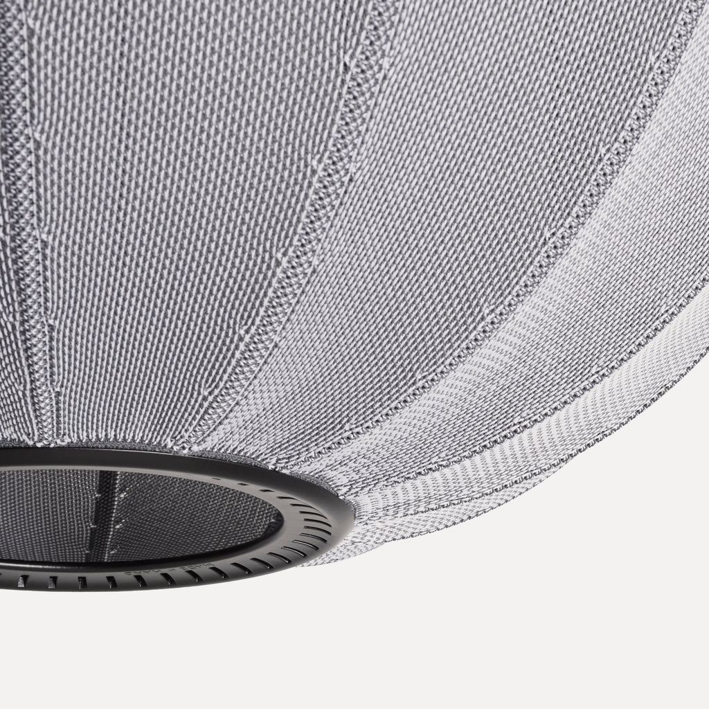 Made by Hand Knit-Wit Ø45 Oval Pendant Lamp, a modern minimalist pendant lamp featuring a unique knitted textile shade in a marled light grey and white weave, creating a soft, warm glow. Its distinctive oval, globe-like silhouette is supported by a sleek matte black metal frame.