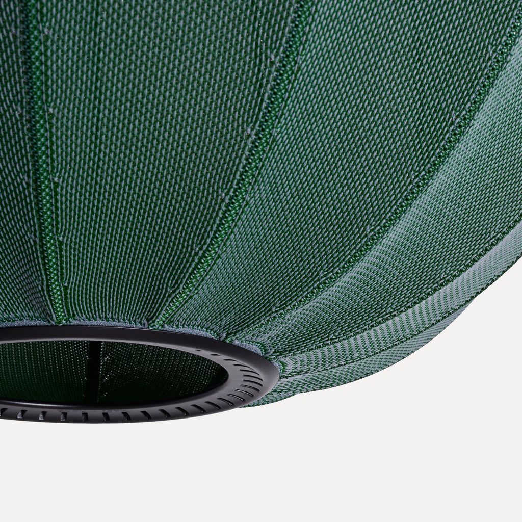 Made by Hand Knit-Wit Ø45 Oval Pendant Lamp, a modern Scandinavian pendant lamp featuring a dark green knitted textile shade with a distinct ribbed texture and a contrasting black metal ring. This contemporary oval ceiling light provides soft, diffused illumination, perfect for a minimalist living room or as a stylish dining room accent.