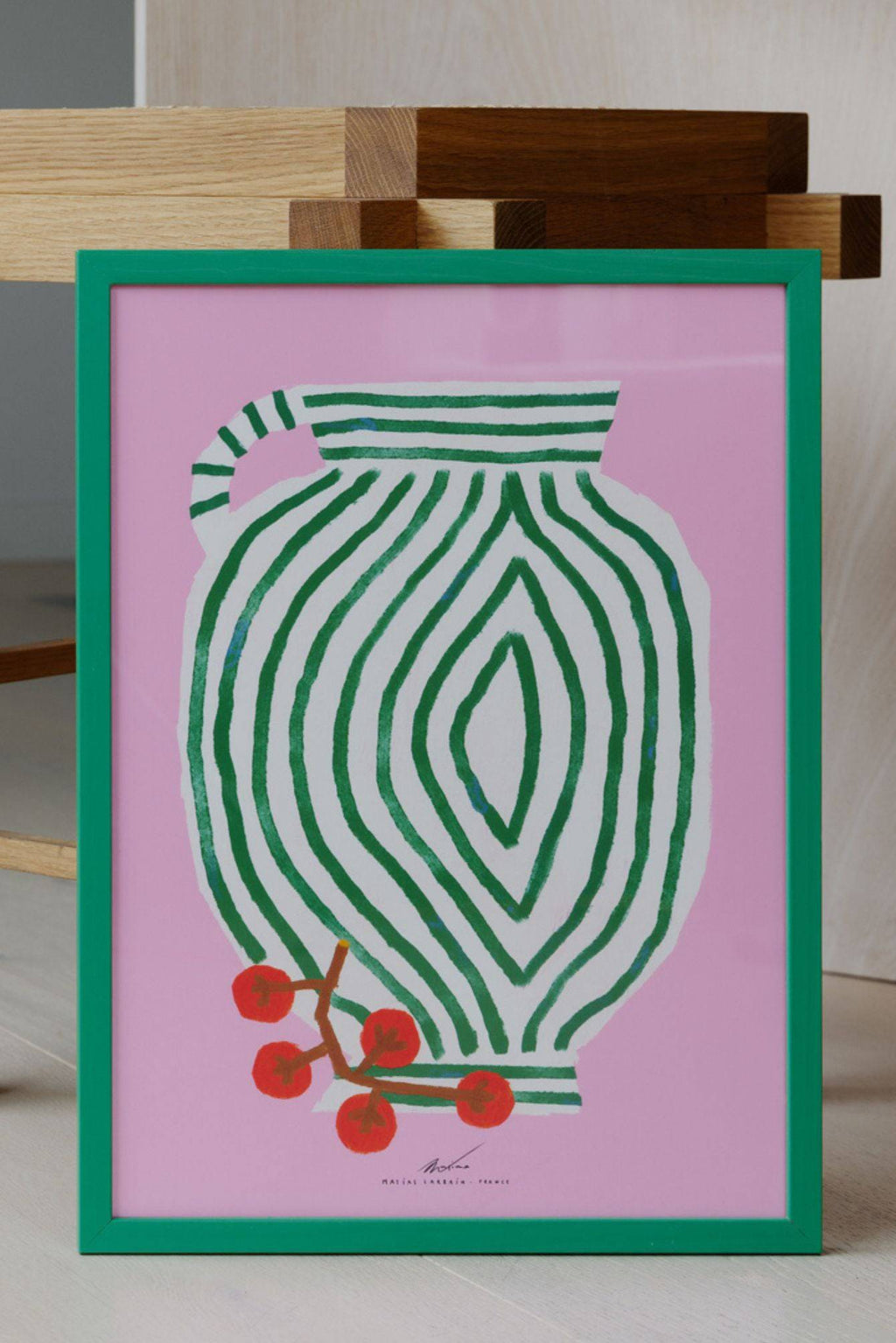The Poster Club Vase and Currants, a vibrant contemporary art print featuring an abstract white vase with bold green stripes set against a bright pink background, accented with a cluster of vivid red currants. This playful framed poster, enclosed in a matching bold green frame, is ideal for adding a pop of color to modern living rooms, nurseries, or kitchen wall art collections.