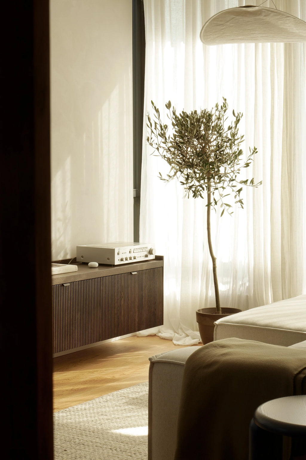 TAMO Meda 2 TV Unit, a luxury dark wood slatted console with sleek minimalist handles and a white audio receiver, displayed in a bright, modern living room. Perfect for contemporary interiors.