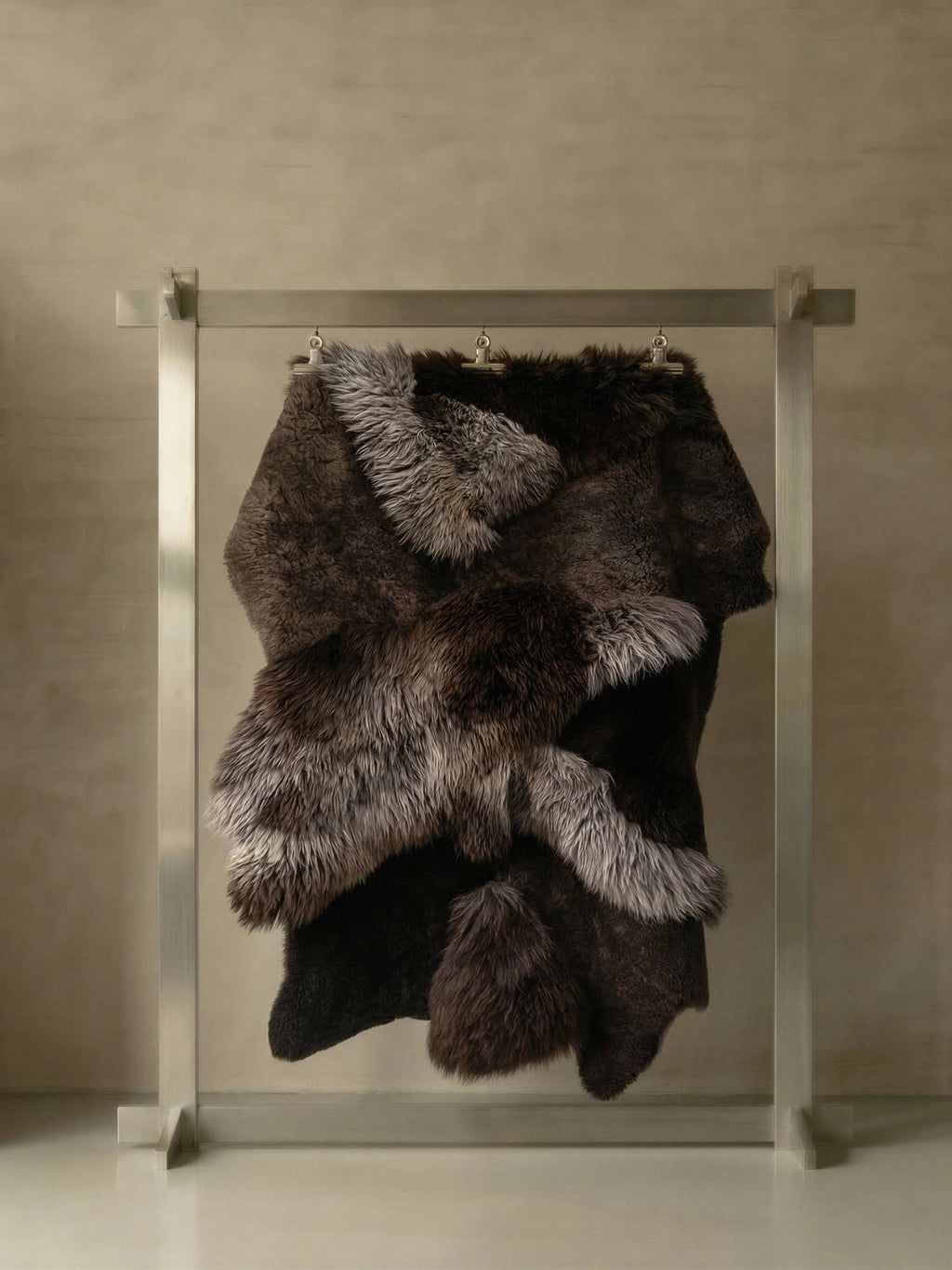 TCL Studios Brown Sheepskin Patchwork Rug, a luxurious multi-toned genuine sheepskin rug featuring a rich blend of dark brown, charcoal grey, and warm grey long-haired and curly shorn patches.