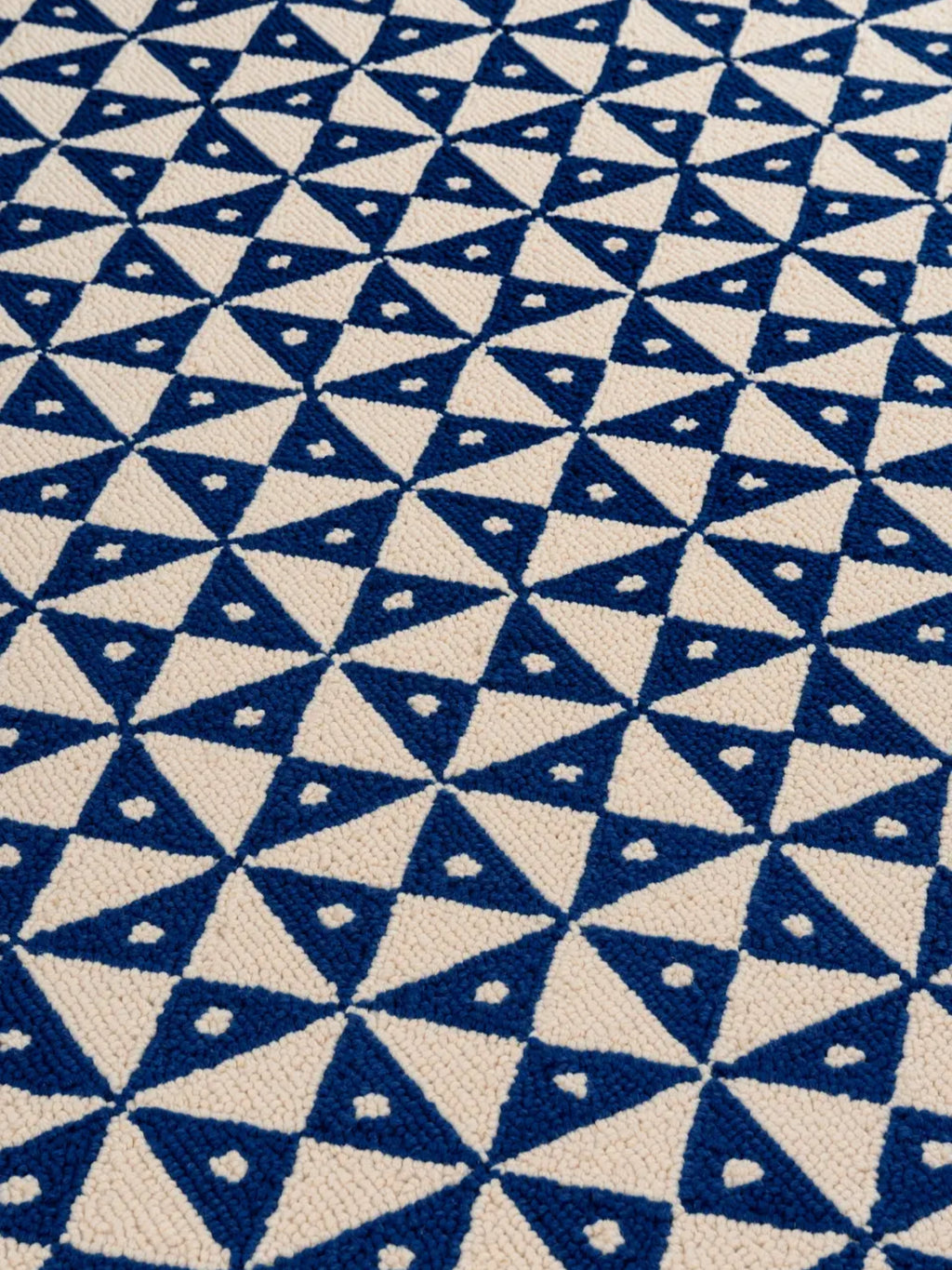 alp_ Mosaic Signature Rug, a hand-tufted wool area rug showcasing a striking geometric mosaic pattern. The design features alternating royal blue and soft cream triangles arranged in a repeating, interlocking motif, with a plush loop pile creating a rich, textured surface. This modern geometric rug is ideal for adding a vibrant focal point to contemporary living rooms, minimalist bedrooms, or eclectic home offices.