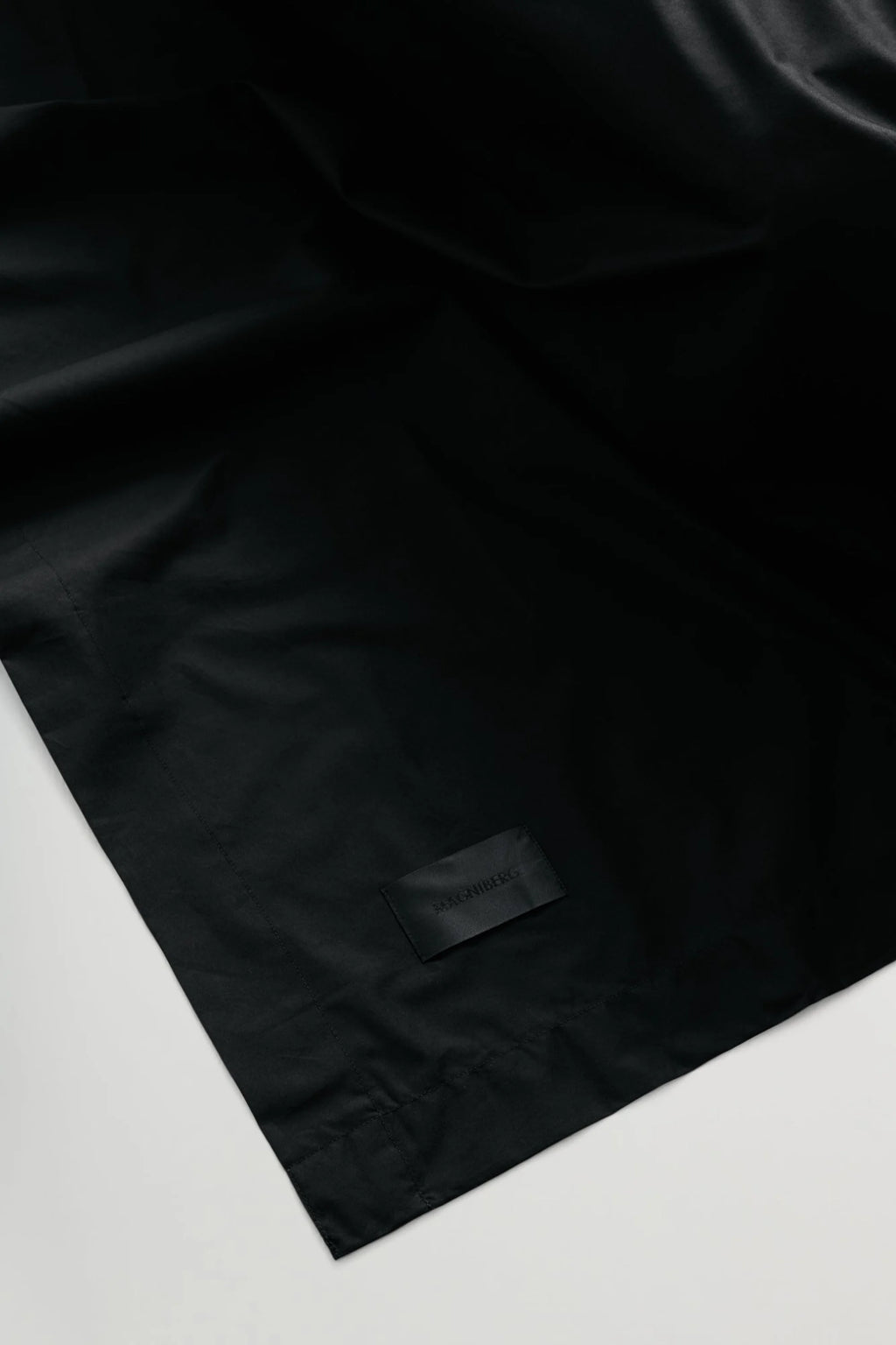 Magniberg Mother Poplin Flat Sheet, a solid black, crisp cotton poplin flat sheet featuring a smooth, matte texture and clean, modern design. This luxurious and minimalist black bedding is ideal for elevating a contemporary bedroom or achieving a sophisticated aesthetic.