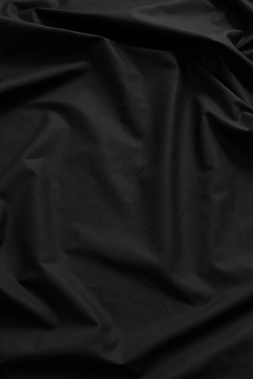 Magniberg Mother Poplin Flat Sheet, a luxurious black cotton poplin flat sheet featuring a smooth, crisp yet incredibly soft texture that drapes elegantly with subtle folds and natural shadows.