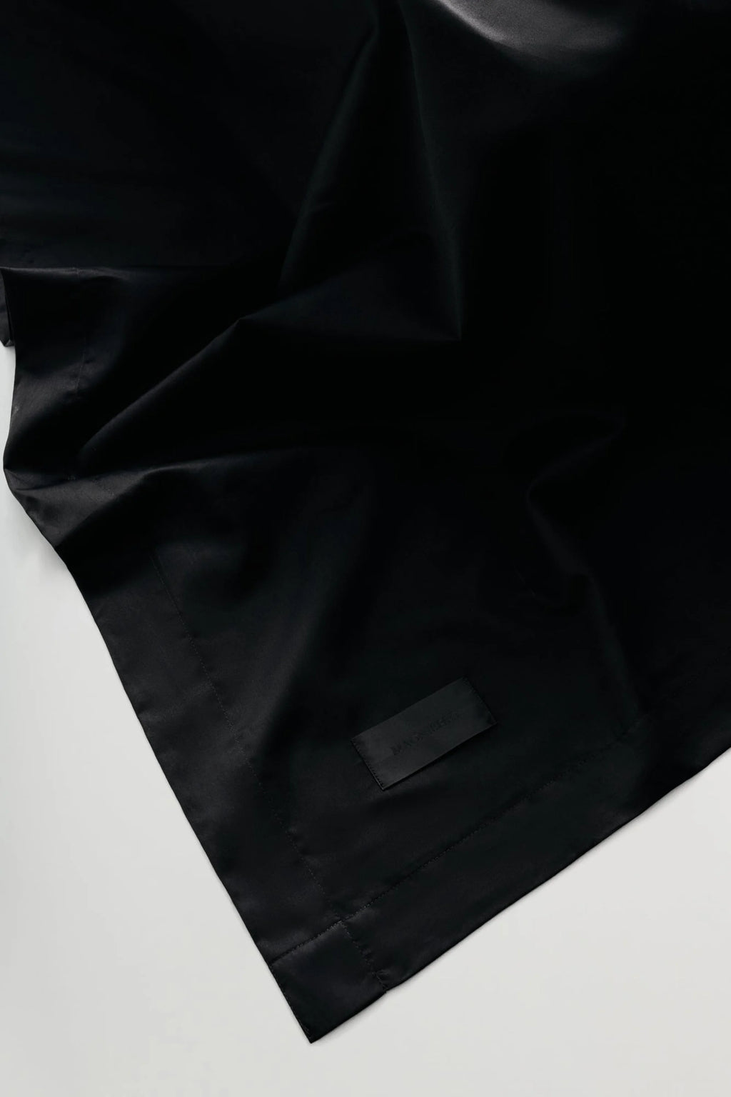 Magniberg Mother Sateen Flat Sheet, a luxurious deep black sateen flat sheet crafted from premium cotton with a smooth, silky texture and a subtle, elegant sheen. This modern minimalist bedding features crisp edges and soft draping, making it an ideal choice for creating a sophisticated and contemporary bedroom aesthetic.