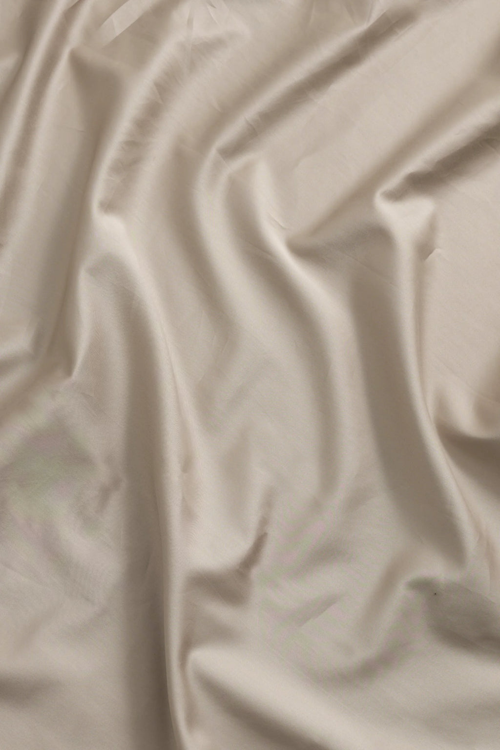 Magniberg Mother Sateen Flat Sheet, a luxurious light beige sateen fabric with a smooth, lustrous finish and soft, organic draping, creating subtle shadows and highlights. This premium taupe sateen flat sheet is perfect for contemporary bedroom decor or minimalist luxury bedding collections.