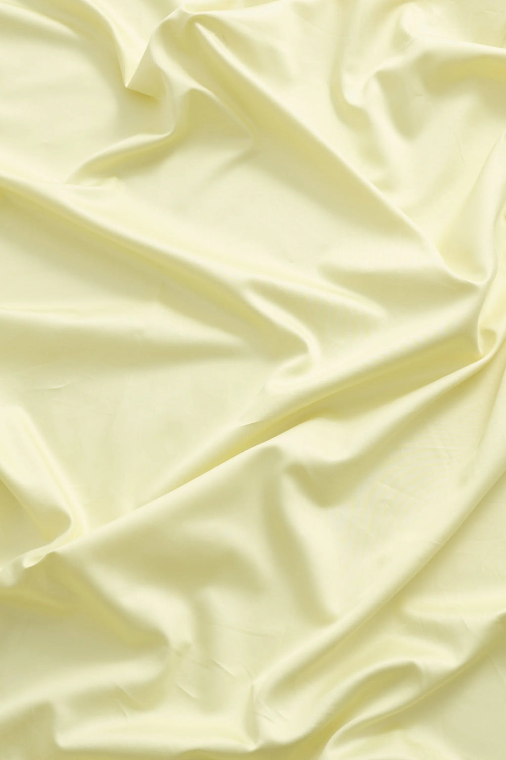 Magniberg Mother Sateen Flat Sheet, a luxurious pale yellow sateen flat sheet with a smooth, lustrous finish and soft drapes, showcasing its high-quality sateen fabric. This creamy yellow bed sheet is perfect for creating a modern minimalist bedroom or adding a touch of contemporary luxury to any sleeping space.