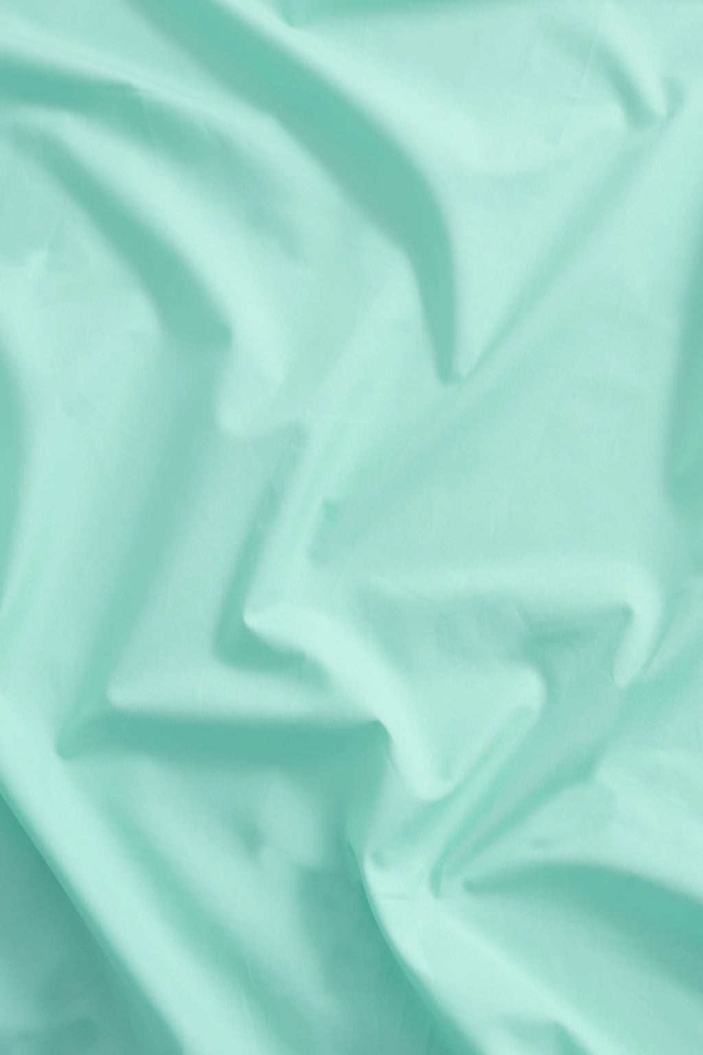 Magniberg Mother Poplin Flat Sheet, a luxurious and crisp light mint green cotton poplin flat sheet, showcasing a smooth, soft texture with elegant, natural drapes and gentle shadows. This contemporary and minimalist bedding is perfect for creating a serene Scandinavian bedroom aesthetic or adding a fresh pop of color to any modern interior.