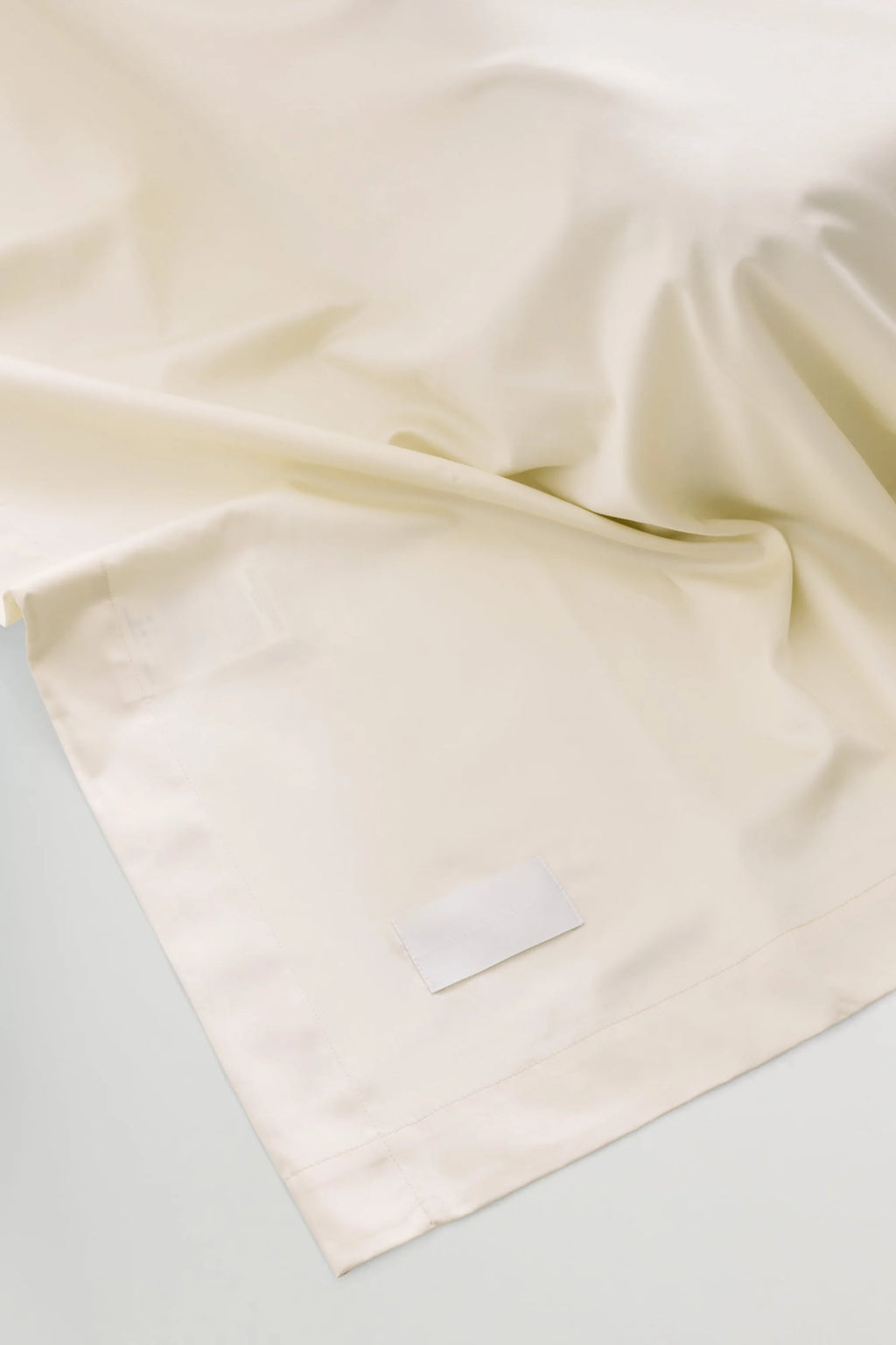 Magniberg Mother Sateen Flat Sheet, a luxurious cream sateen cotton flat sheet featuring a smooth, subtly lustrous finish and a soft, elegant drape, designed for contemporary bedroom interiors. This premium off-white bedding provides a minimalist aesthetic, perfect for enhancing any modern bedroom decor.