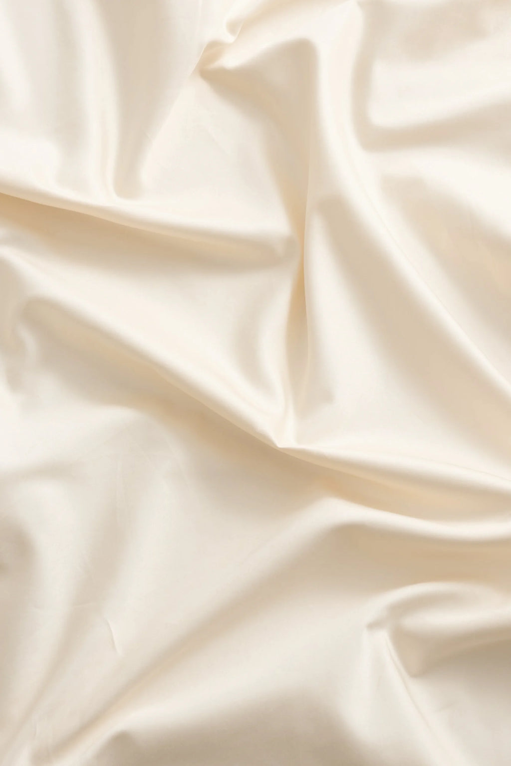 Magniberg Mother Sateen Flat Sheet, a luxurious cream-colored sateen sheet with a soft, smooth texture and subtle, elegant sheen, featuring natural drapes and gentle folds across its surface. Crafted from premium cotton sateen, this off-white bedding offers a rich, comforting feel, ideal for creating a minimalist and serene bedroom aesthetic or adding a touch of contemporary luxury to any master bedroom.