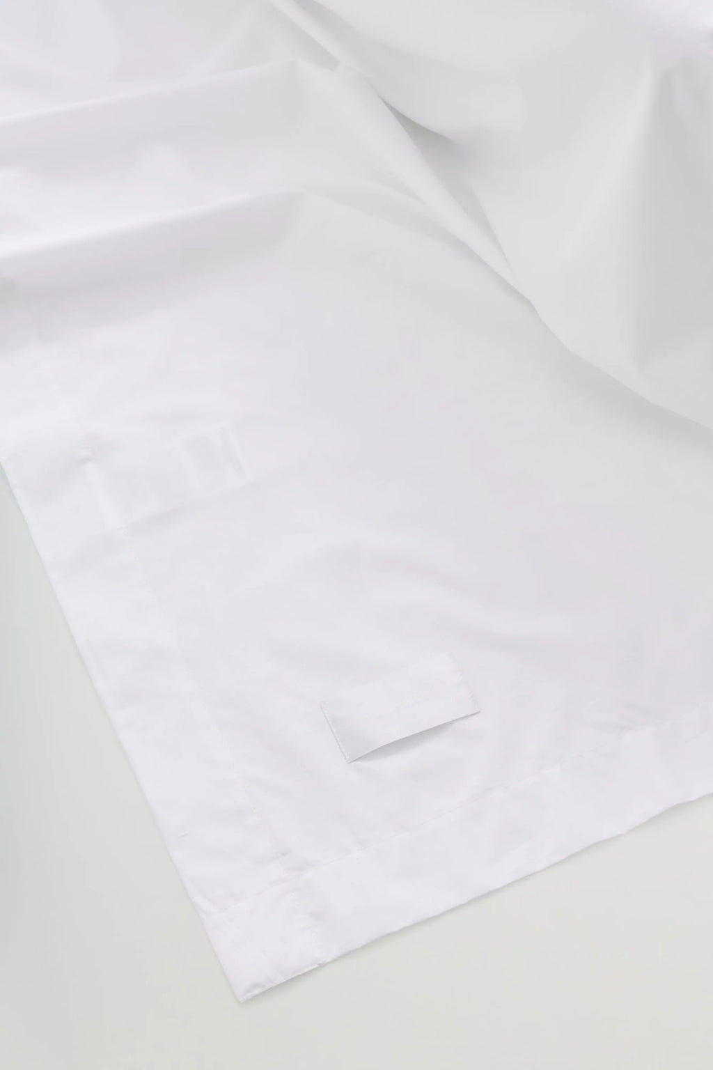 Magniberg Mother Poplin Flat Sheet, a crisp white poplin flat sheet crafted from smooth, high-quality cotton, featuring a clean, minimalist design with subtly visible seams and a matte finish. This luxurious white bedding is perfect for creating a contemporary, serene bedroom aesthetic or adding hotel-quality comfort to any modern minimalist interior.