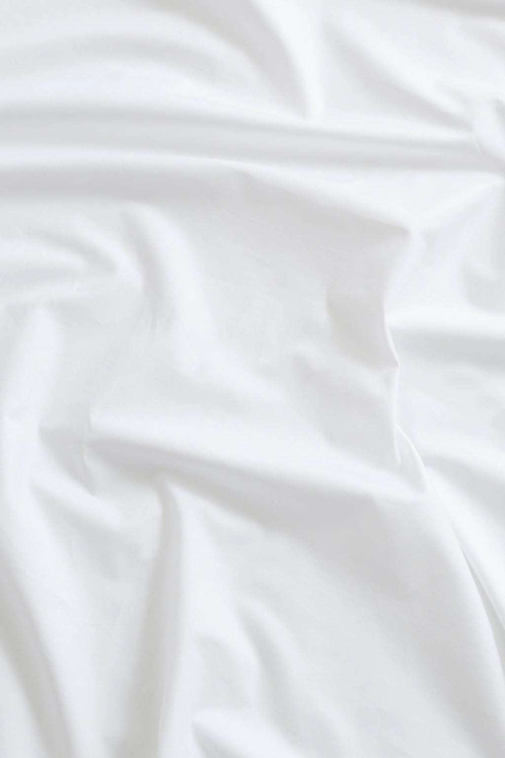 Magniberg Mother Poplin Flat Sheet, a crisp white pure poplin cotton flat sheet featuring a smooth, matte finish and subtle, soft folds that suggest premium comfort.