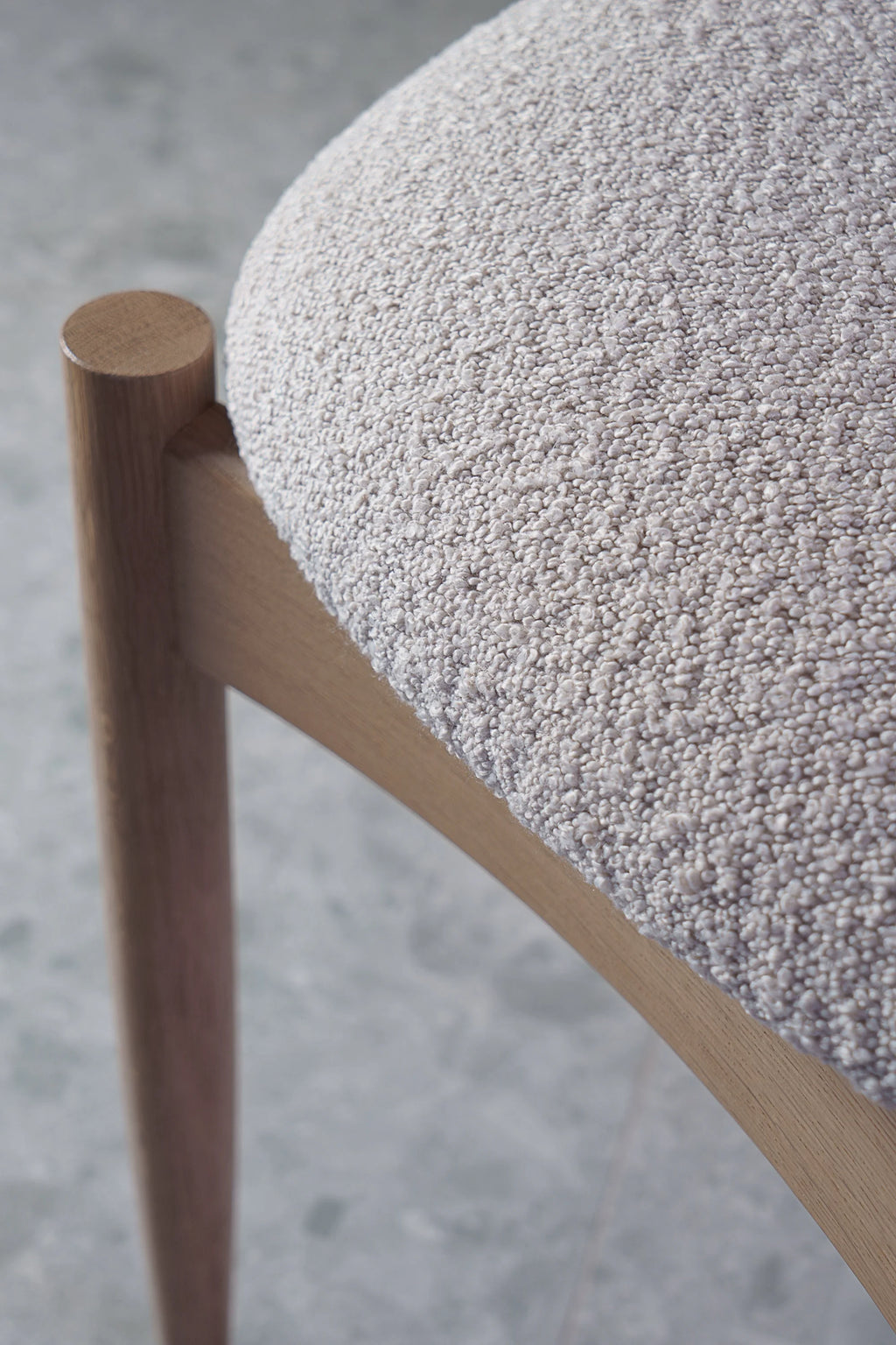 TAMO Kemi Chair, a minimalist Scandinavian dining chair featuring a light natural solid oak wood frame with a rounded cylindrical leg and a plush light grey bouclé upholstered seat. This organic modern chair offers a cozy texture, perfect for contemporary dining rooms or as an elegant accent chair.
