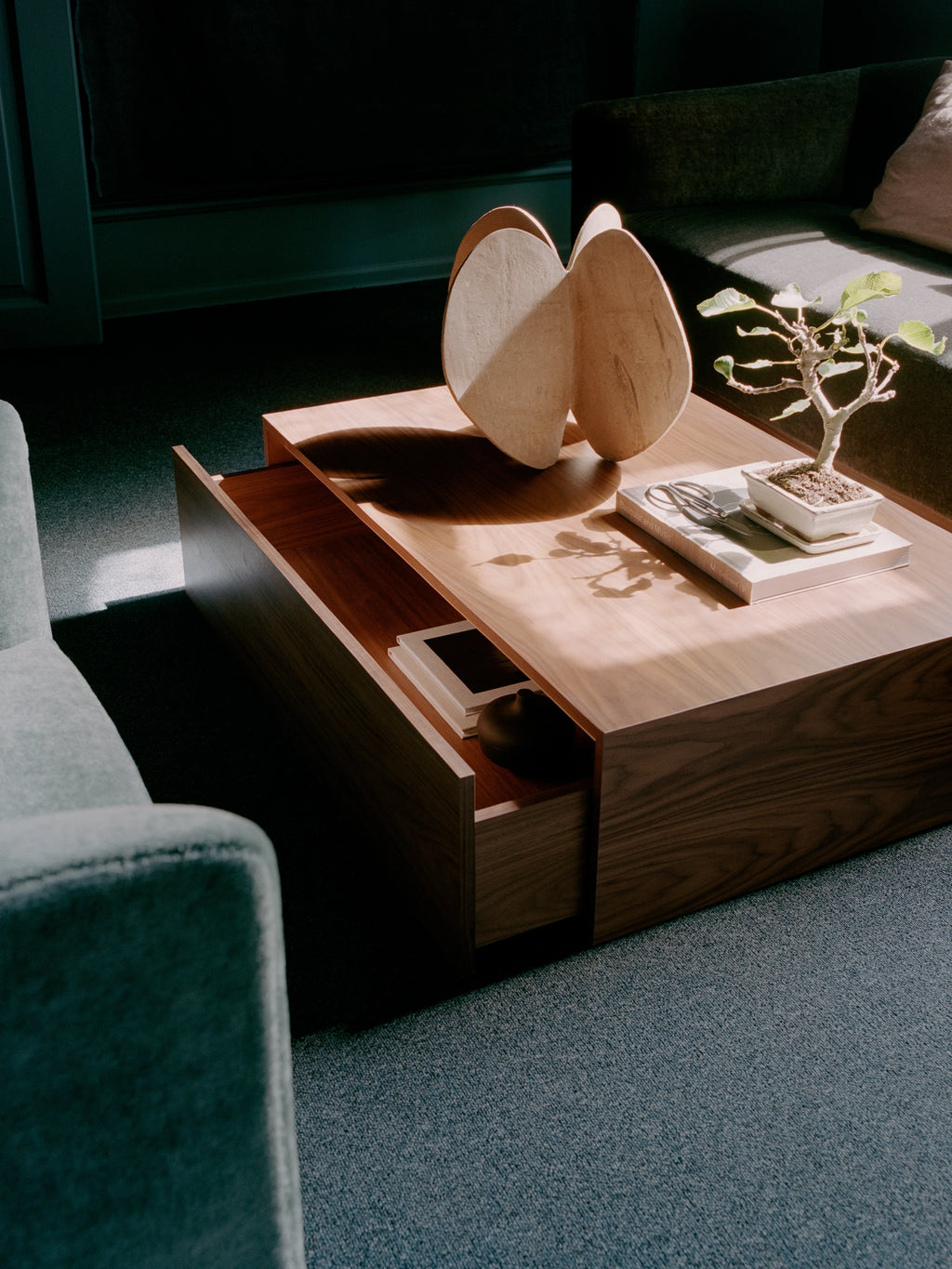 New Works Mass Coffee Table w. Drawer, a sleek modern minimalist coffee table crafted from dark walnut solid wood with a rich, visible grain and a distinctive floating top design. This rectangular coffee table features a full-width integrated drawer, offering discreet storage for a tidy living room. Ideal as a contemporary living room centerpiece or for Scandinavian-inspired interiors.
