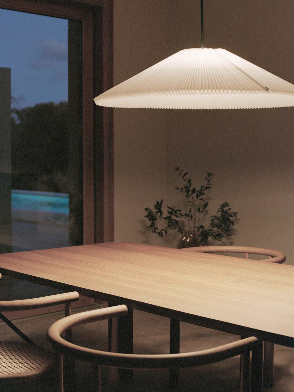 New Works Nebra Pendant Lamp, an elegant off-white pleated paper pendant lamp featuring a wide, shallow conical shade with intricate, layered pleats and a distinctive ridged edge. This modern minimalist ceiling light provides soft, diffused illumination, perfect for Scandinavian dining rooms, Japandi living spaces, or contemporary organic modern interiors.