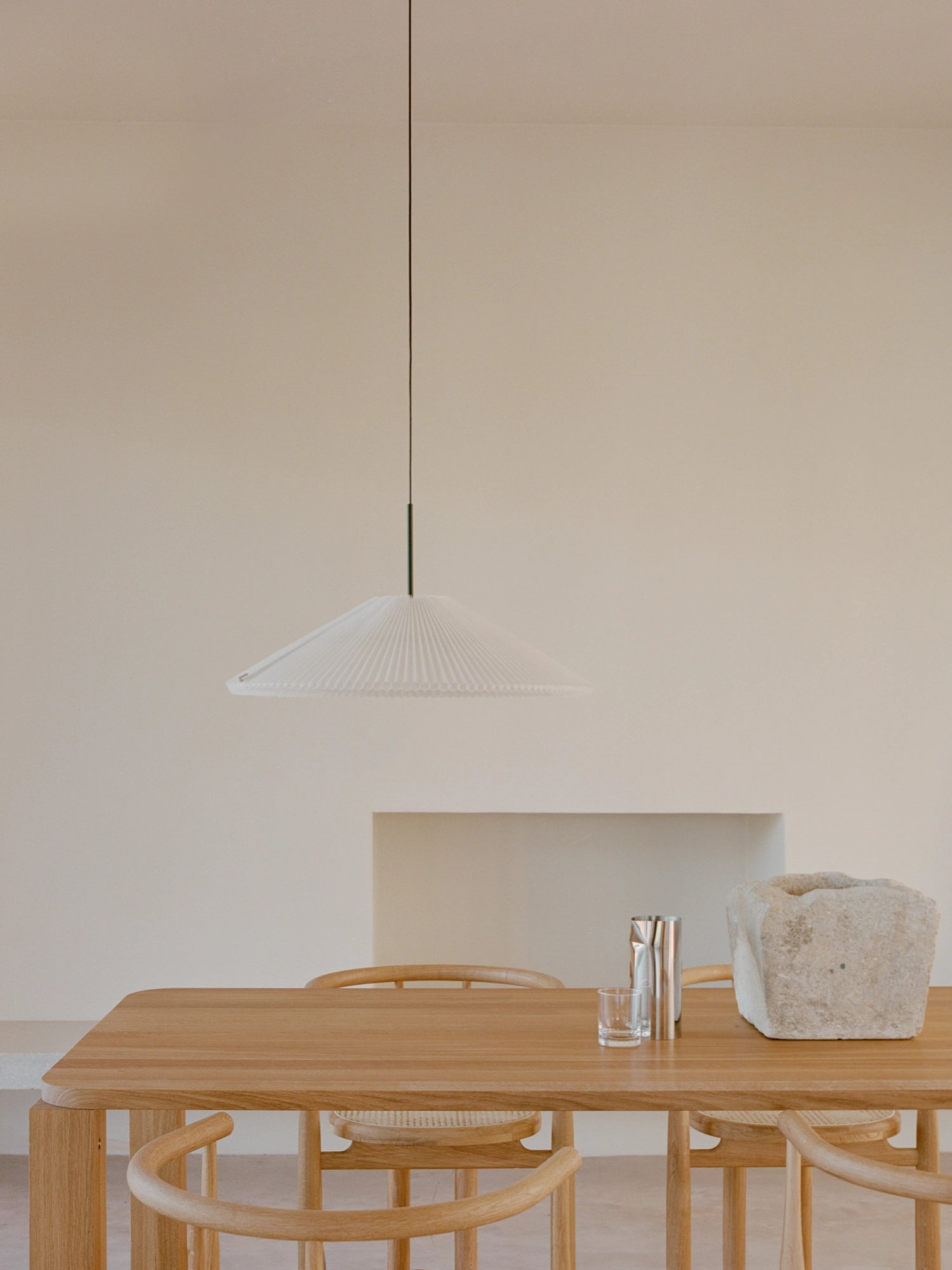 New Works Nebra Pendant Lamp, a modern minimalist ceiling light featuring a wide, shallow white pleated shade with a delicate ribbed texture and a sleek black suspension cord. This contemporary pendant lamp provides soft, diffused illumination, making it ideal for Scandinavian dining rooms, minimalist living spaces, or organic modern interiors.