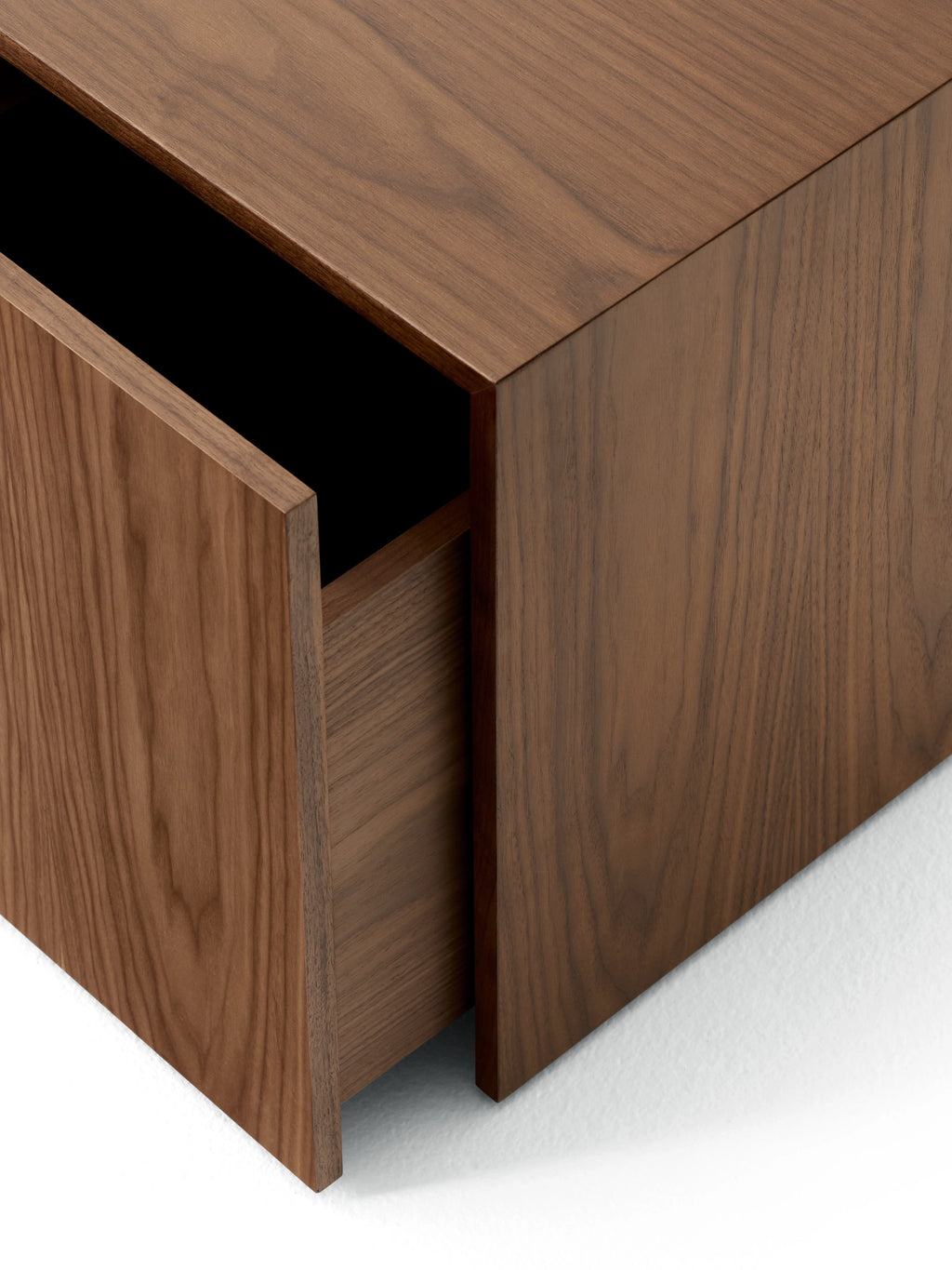 New Works Mass Side Table w. Drawer, a modern minimalist side table crafted from rich dark walnut wood with a smooth, visible grain and a seamlessly integrated pull-out drawer featuring a matte black interior. This contemporary storage furniture piece offers clean lines and a sculptural form, perfect as a Scandinavian bedside table or elegant living room end table.