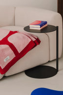 ###
A modern Ande Side Table with a sleek black metal frame and a round glass top