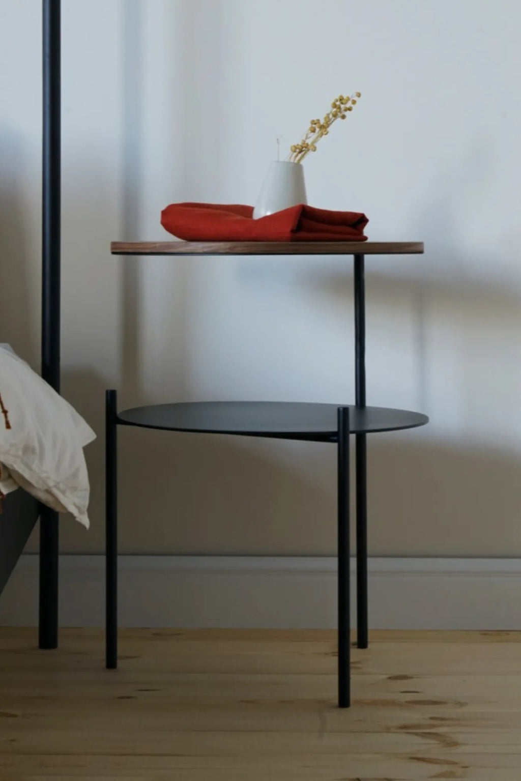 noo.ma Tu Bedside Table, a sleek modern minimalist two-tier bedside table with a matte black metal frame. It features a rich dark walnut-toned rectangular upper shelf and a matte black circular metal lower shelf, providing both style and practical storage. Ideal as a contemporary nightstand for Scandinavian bedrooms or industrial chic living rooms.