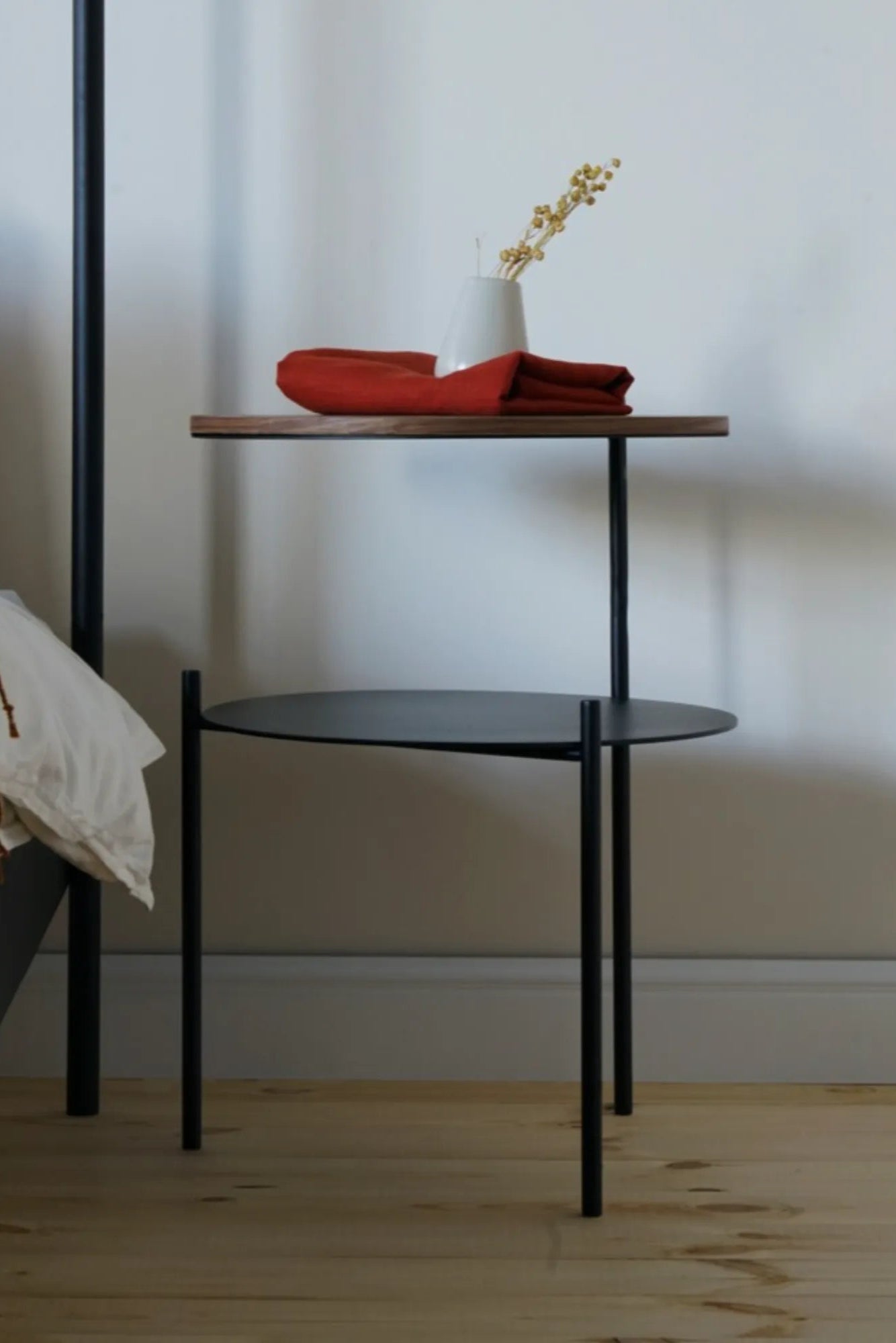 noo.ma Tu Bedside Table, a sleek modern minimalist two-tier bedside table with a matte black metal frame. It features a rich dark walnut-toned rectangular upper shelf and a matte black circular metal lower shelf, providing both style and practical storage. Ideal as a contemporary nightstand for Scandinavian bedrooms or industrial chic living rooms.