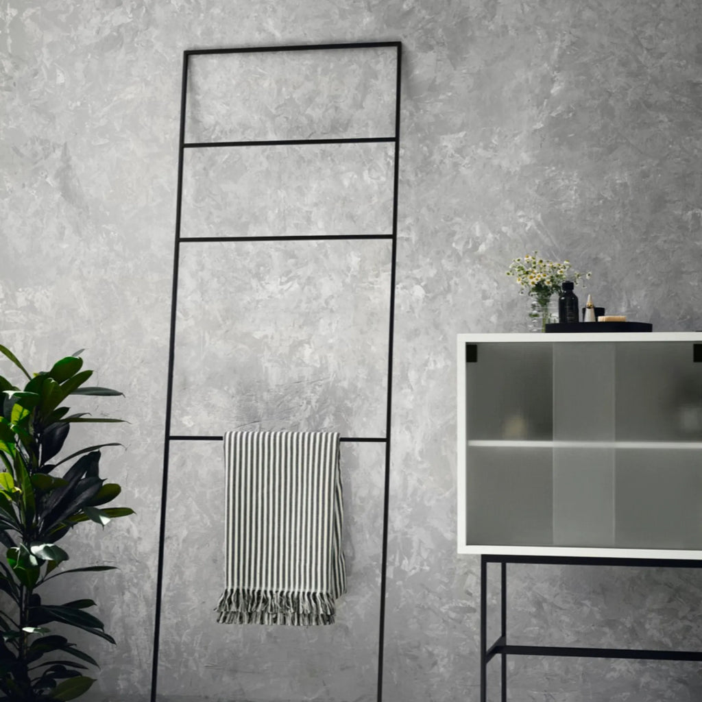 noo.ma Tows Ladder, a tall modern minimalist leaning towel ladder crafted from durable matte black metal. Its sleek, rectangular frame with five horizontal rungs provides versatile storage for towels in bathrooms or blankets in living rooms. An ideal industrial chic or Scandinavian accent for contemporary homes.