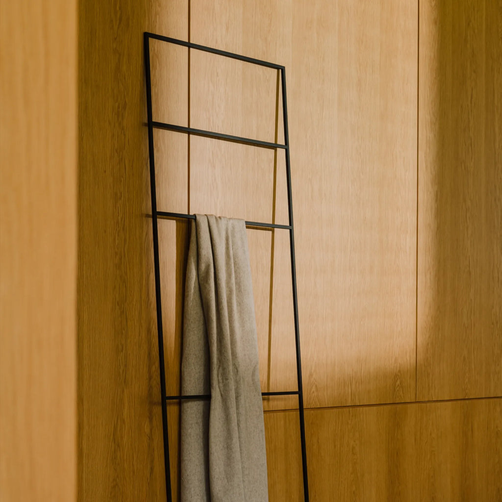 noo.ma Tows Ladder, a sleek modern minimalist lean-to ladder crafted from durable matte black metal with clean lines and a functional geometric design. This contemporary towel ladder provides stylish storage and display for blankets or towels. Ideal for Scandinavian bathrooms, minimalist bedrooms, or industrial chic living rooms.