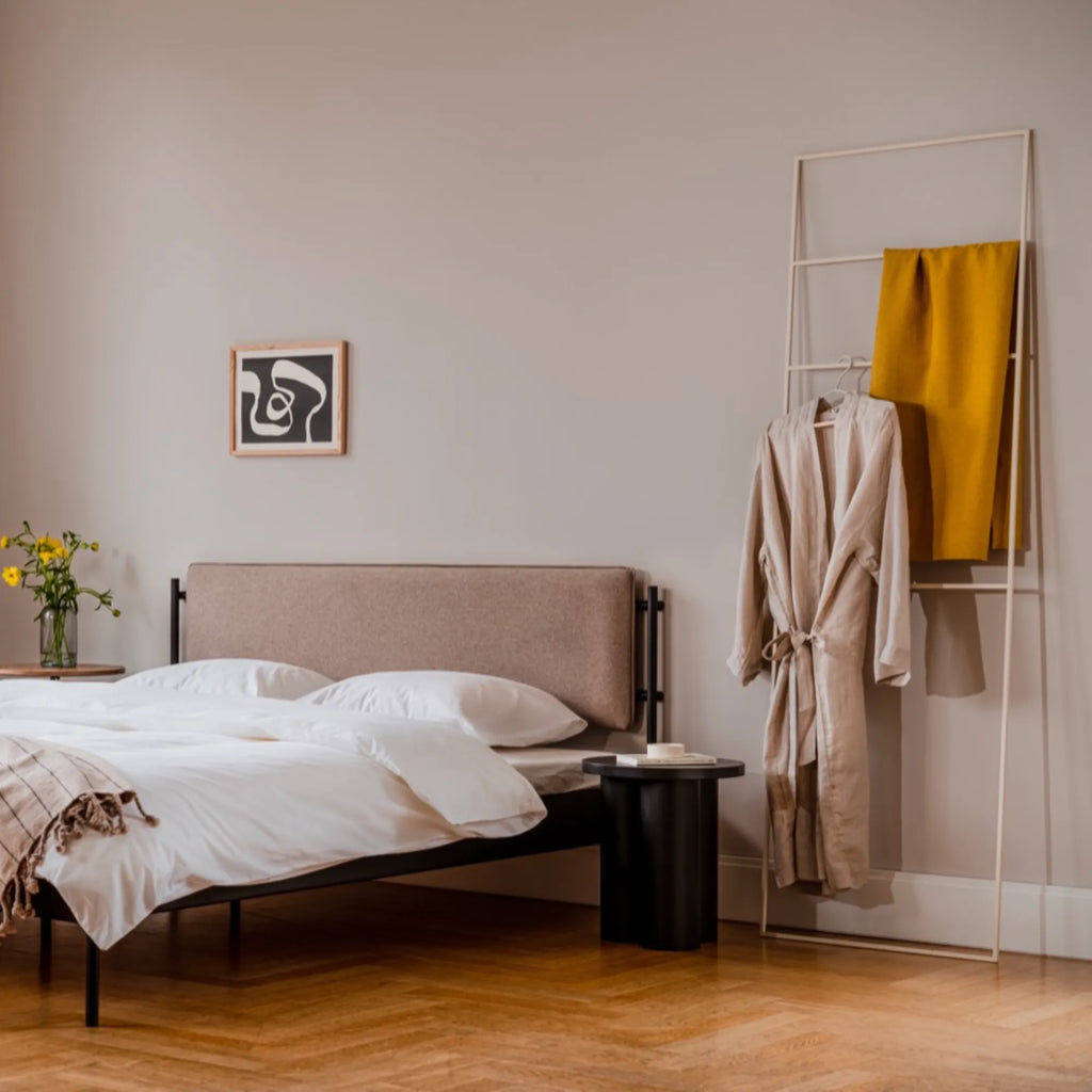 noo.ma Tows Ladder, a modern minimalist towel ladder crafted from matte cream-colored metal with a clean rectangular frame and multiple horizontal bars. This Scandinavian-inspired freestanding towel holder is perfect for organizing towels in a bathroom or displaying blankets and clothing in a contemporary bedroom.