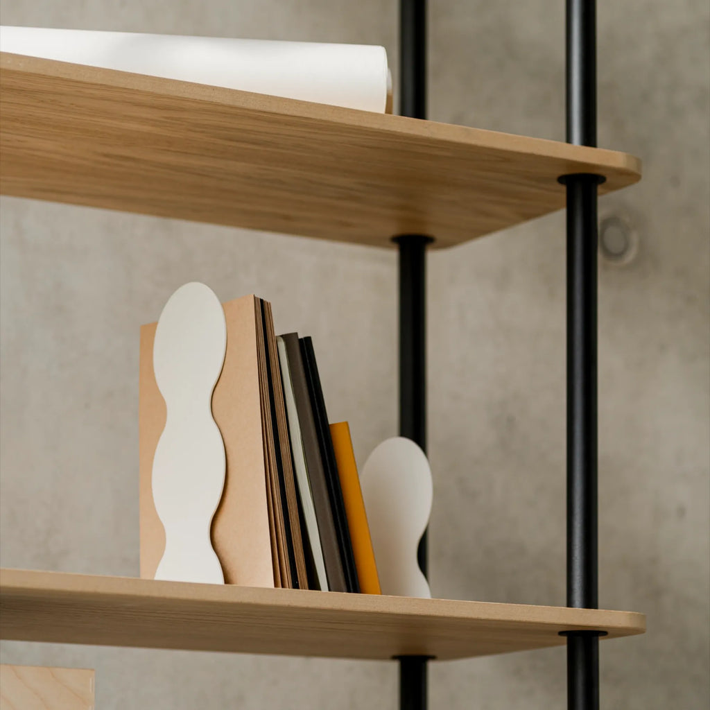 noo.ma Teidi Shelving Unit 5-tier, a modern minimalist bookshelf showcasing light natural oak wood shelves with smoothly rounded corners, elegantly supported by slim matte black metal vertical poles. This Scandinavian-inspired open shelving unit provides versatile storage for books and decorative objects, ideal for contemporary living rooms, home offices, or cozy bedroom organization.