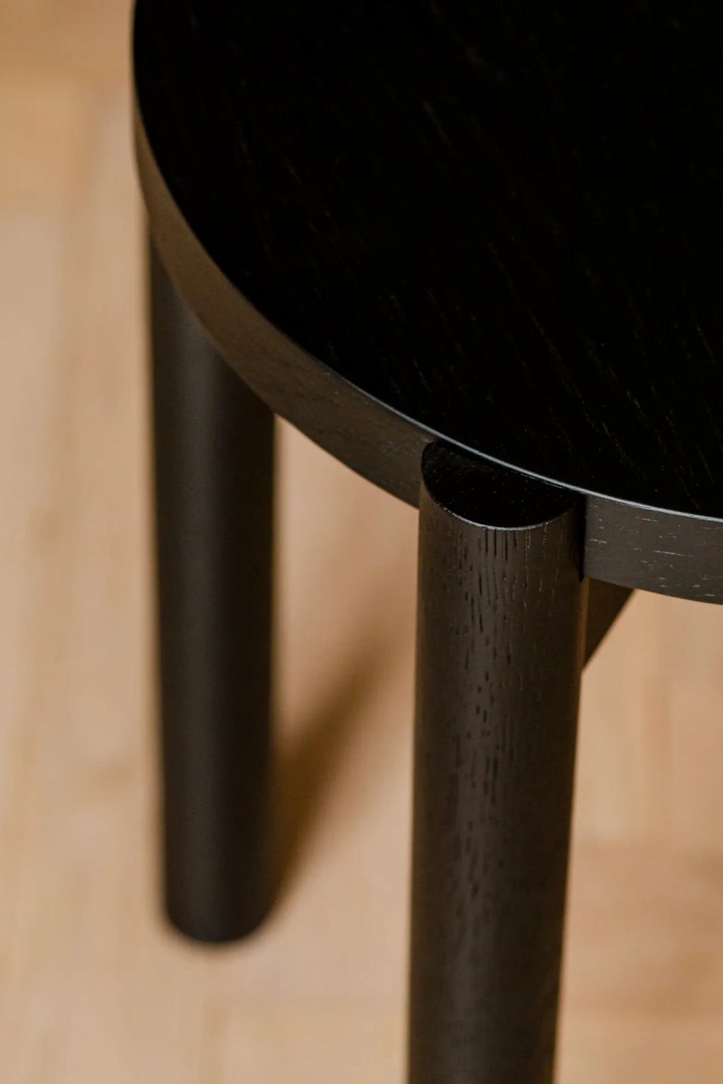 noo.ma Hopp Stool, a modern minimalist round stool crafted from solid black oak wood, showcasing a smooth circular top and sturdy cylindrical legs seamlessly integrated with a subtle organic modern silhouette.