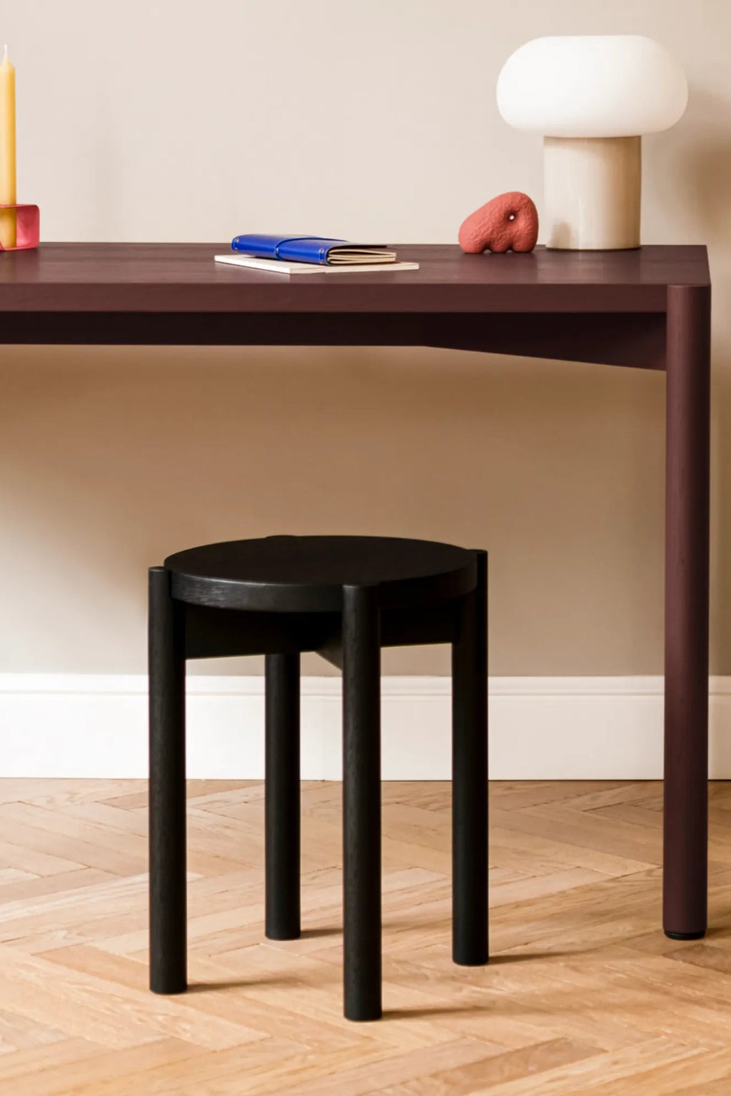 noo.ma Hopp Stool, a modern minimalist stool crafted from solid wood with a sleek matte black finish, featuring a perfectly round seat and three robust cylindrical legs for a clean, stable profile. This versatile black accent stool embodies contemporary Scandinavian design, ideal for a chic home office, a stylish bedroom accent, or as a functional side table in a modern living room.