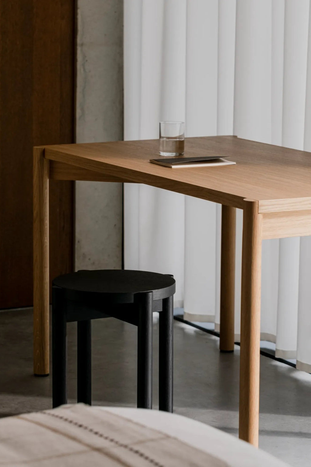 noo.ma Hopp Stool, a modern minimalist solid wood stool featuring a sleek matte black finish and a round seat supported by four sturdy cylindrical legs. This contemporary black accent stool boasts clean Scandinavian lines and visible wood grain texture, offering a versatile design. Ideal as a stylish side table, entryway stool, or bedroom accent for modern living spaces and japandi interiors.