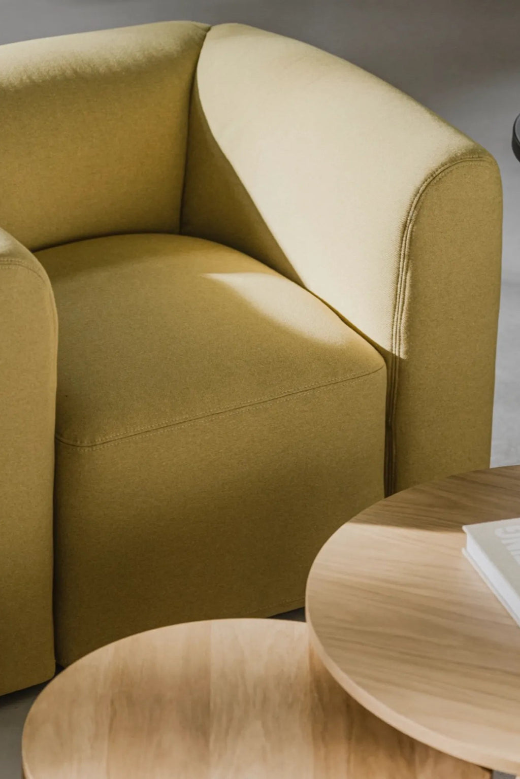 noo.ma Flom Armchair, a contemporary lounge chair upholstered in a warm chartreuse green woven fabric with a soft texture, featuring a gently curved organic silhouette and plush rounded arms. This minimalist accent chair is perfect for adding a pop of color to a Scandinavian living room, modern bedroom, or cozy reading nook.