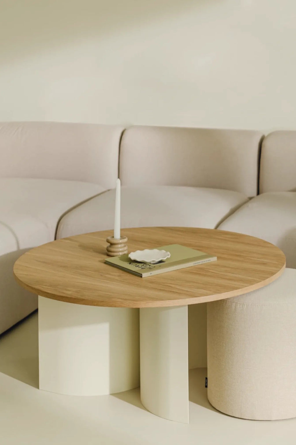 noo.ma Gavo Coffee Table, a modern minimalist round coffee table featuring a smooth, light natural oak wood tabletop supported by two elegantly curved matte cream-white pillar bases. This organic modern design offers a clean aesthetic, perfect as a contemporary living room centerpiece or for Scandinavian-inspired interiors.