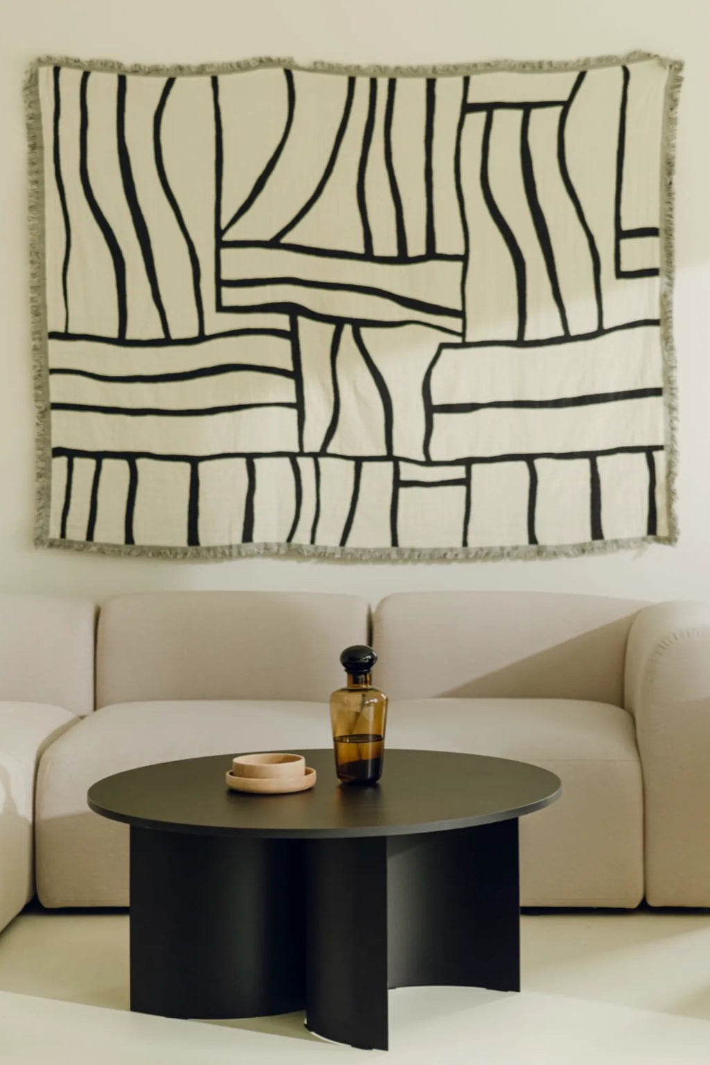 noo.ma Gavo Coffee Table, a round matte black coffee table featuring a distinctive sculptural base composed of three curved cylindrical legs that create a bold, modern silhouette. This contemporary minimalist coffee table is ideal for a living room, adding an organic modern touch to sophisticated interiors.