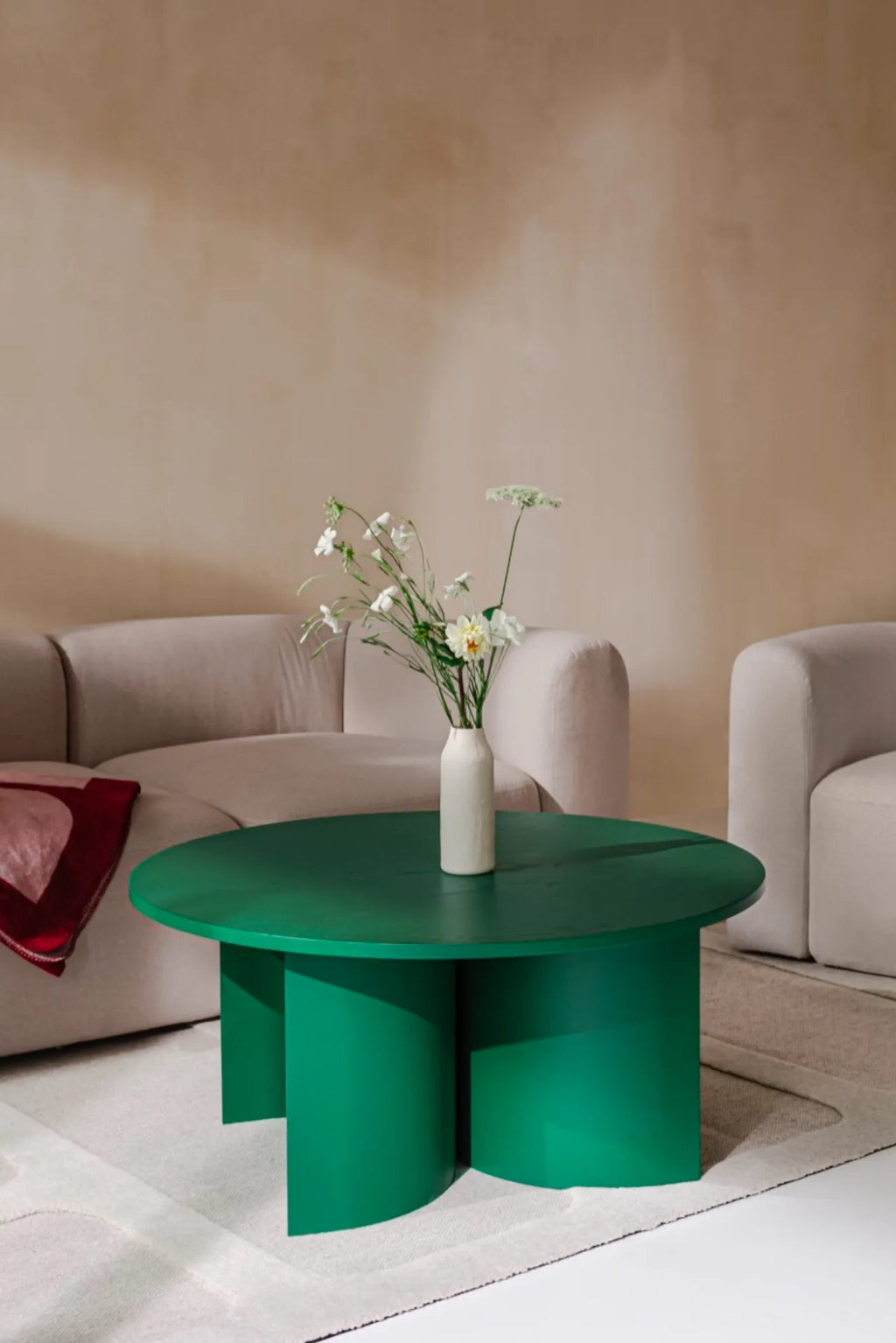 noo.ma Gavo Coffee Table, a bold contemporary coffee table featuring a vibrant emerald green finish on its smooth, round tabletop and unique sculptural base with three semi-cylindrical legs. This modern minimalist design creates a striking statement piece for living rooms. Ideal for adding a pop of color and architectural interest to modern minimalist or contemporary interiors.