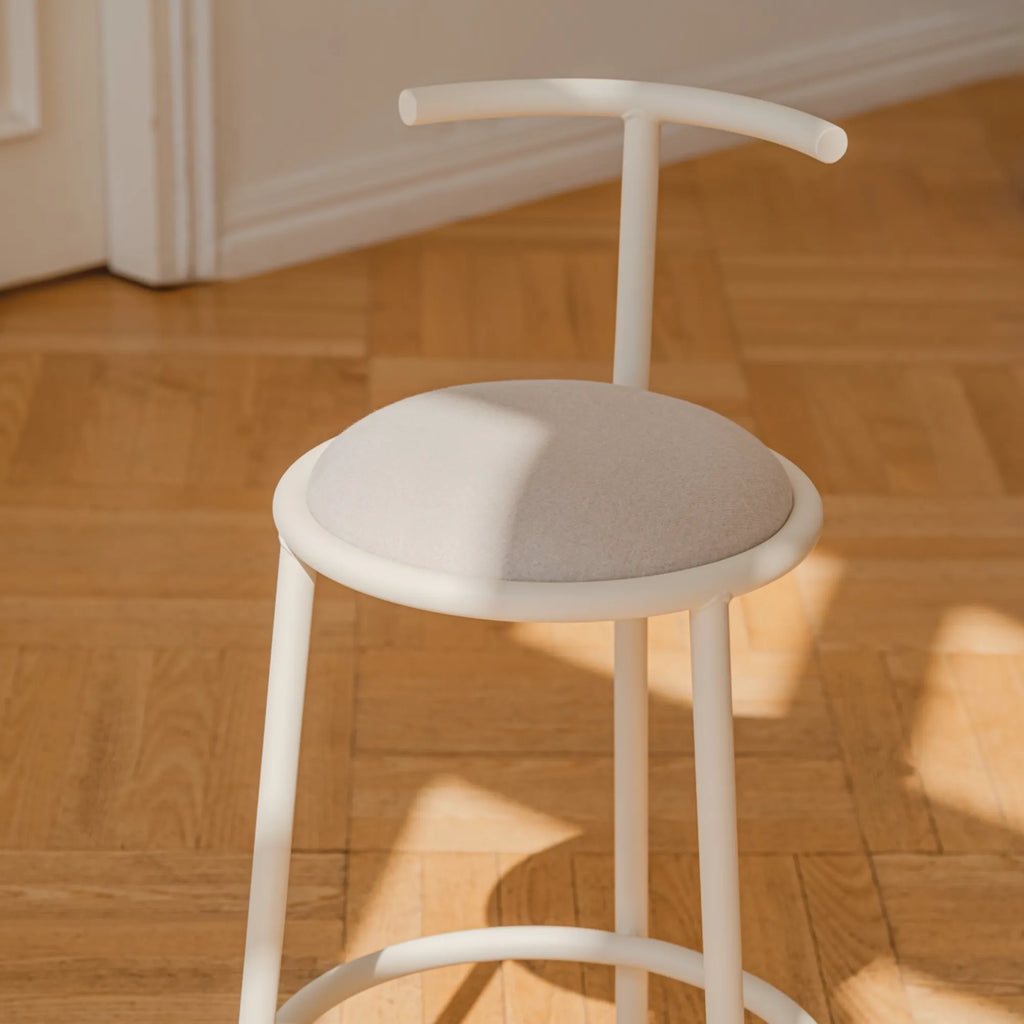 noo.ma Hogo Bar Stool w Backrest, a modern minimalist bar stool featuring a sleek, rounded off-white powder-coated metal frame with a comfortable light grey padded fabric seat and a subtly curved backrest. This contemporary design is perfect as a stylish kitchen island bar stool or for a modern home bar.