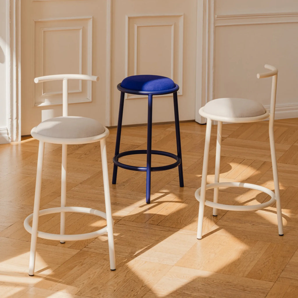 noo.ma Hogo Bar Stool, a trio of modern minimalist bar stools showcasing sleek tubular metal frames and plush upholstered seats with integrated footrests.