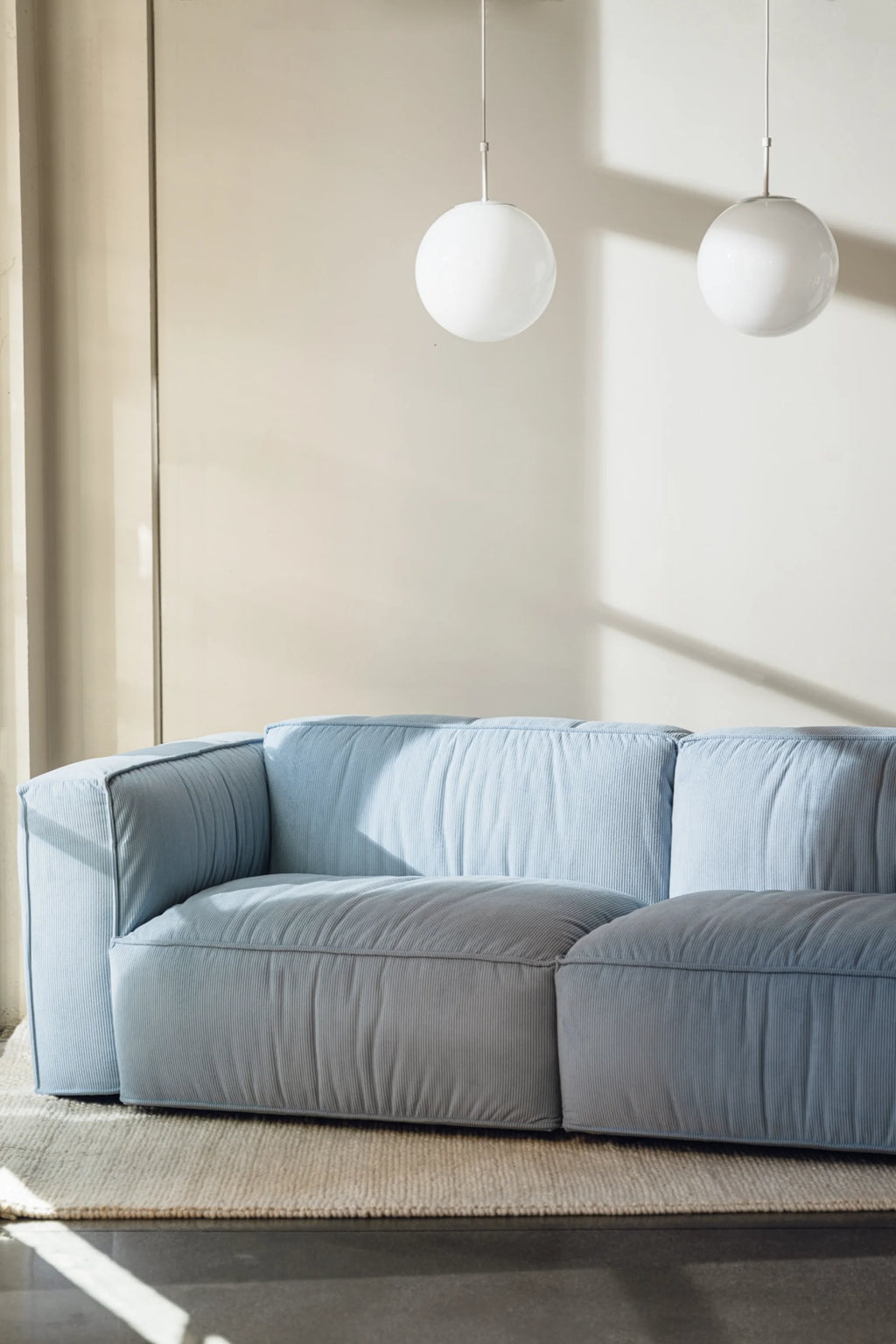 noo.ma Lobi Sofa 3-seater, a light blue modular sofa upholstered in soft, ribbed corduroy fabric, featuring a low-profile design with deep, plush seating and clean, contemporary lines. This modern minimalist 3-seater sofa is perfect for creating a cozy yet stylish focal point in Scandinavian living rooms or spacious apartment interiors.