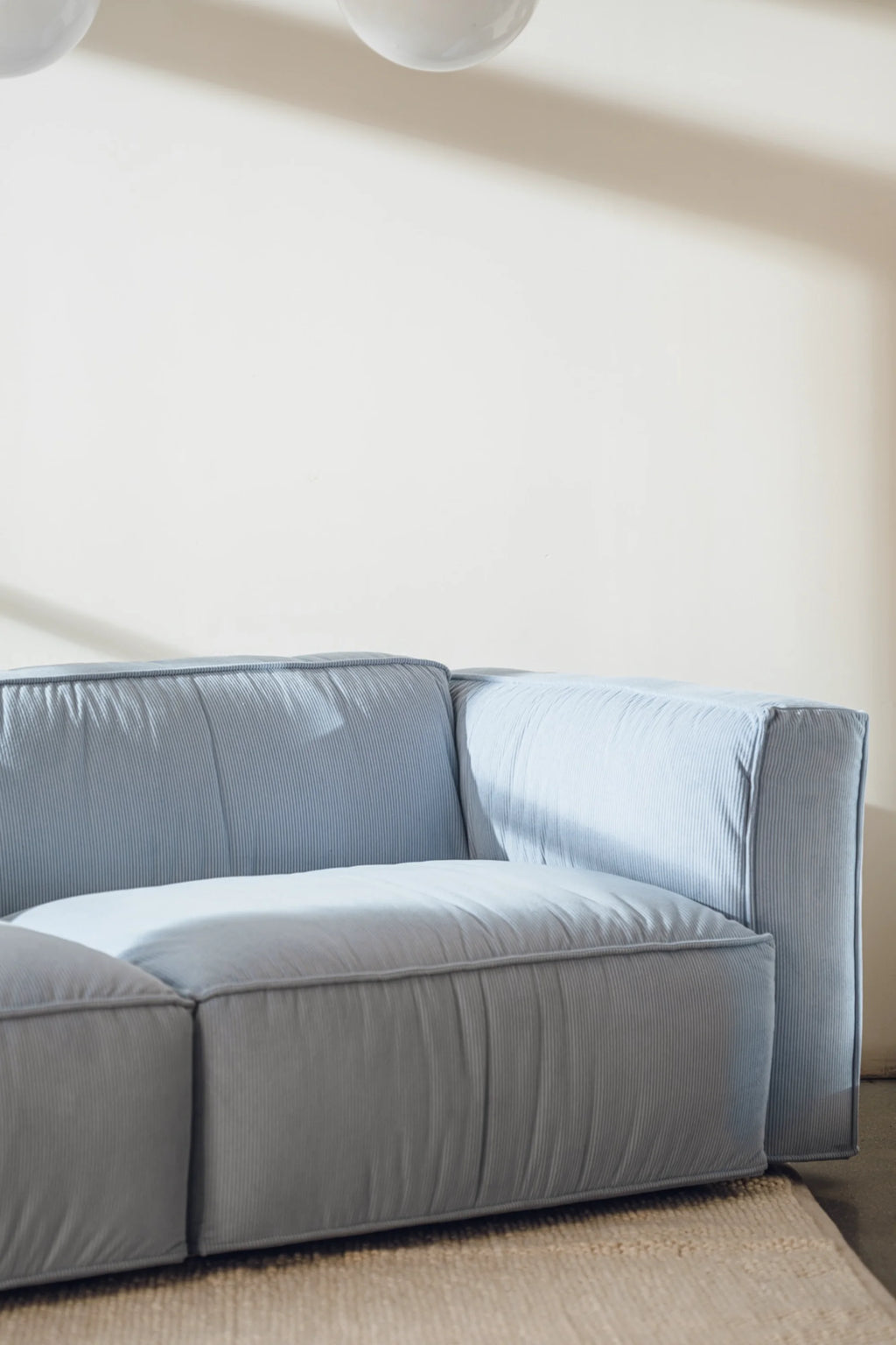 noo.ma Lobi Sofa 3-seater, a contemporary modular sofa upholstered in soft pale blue corduroy fabric featuring a distinctive ribbed texture, deep plush seating, and clean, blocky lines. This modern 3-seater sofa is perfect for creating a cozy lounge space in a minimalist living room or apartment.