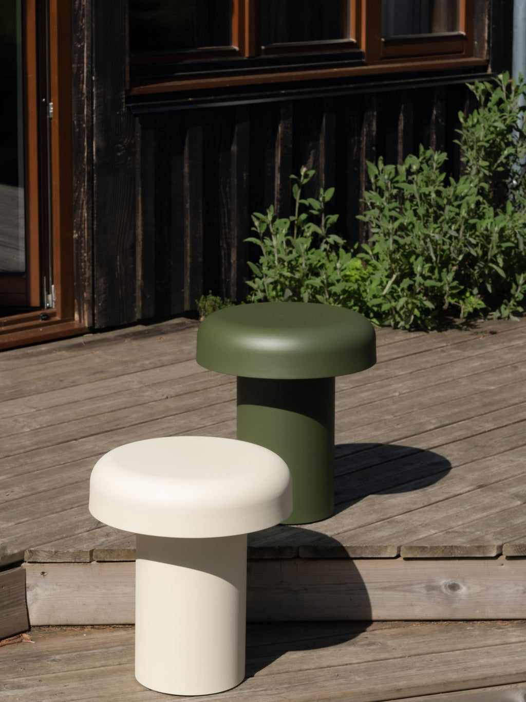 noo.ma Outdoor Miko Side Table, a modern minimalist outdoor accent table designed with a distinctive mushroom-like silhouette, featuring a thick cylindrical base and a wide, rounded flat top. Available in a rich olive green or soft off-white with a smooth, matte, powder-coated finish, these weather-resistant tables are perfect for contemporary patio decor, garden settings, or stylish balcony furniture.