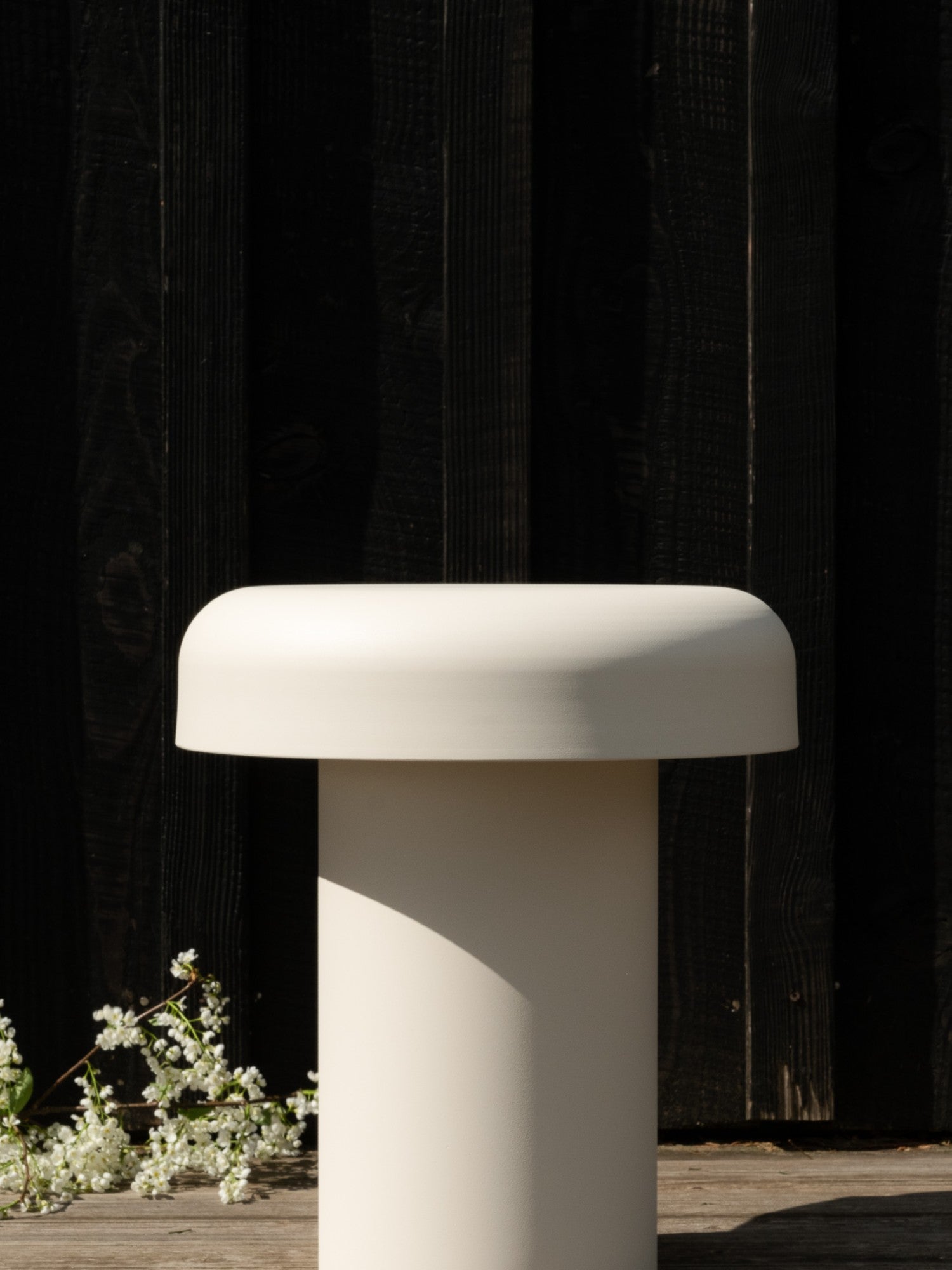 noo.ma Outdoor Miko Side Table, a modern minimalist light beige outdoor side table with a smooth matte finish, featuring a sculptural cylindrical base and a rounded mushroom-like top.