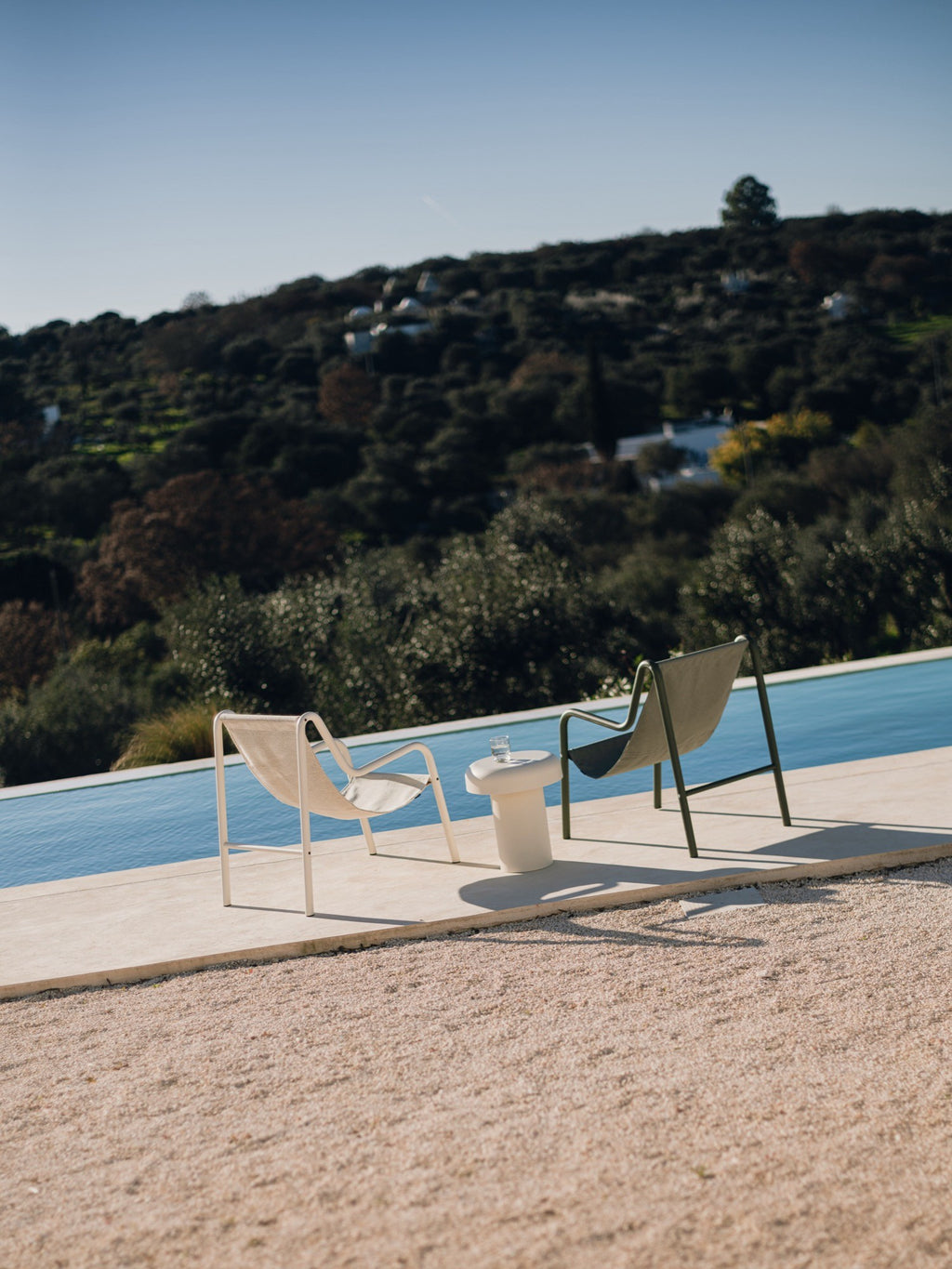 noo.ma Outdoor Miko Side Table, a cream-colored sculptural outdoor side table crafted from durable concrete with a smooth, matte finish. It features an organic, pebble-shaped top on a sturdy cylindrical base, embodying an organic modern and minimalist design. This contemporary outdoor accent table is perfect for poolside lounging, patio decor, or garden settings.