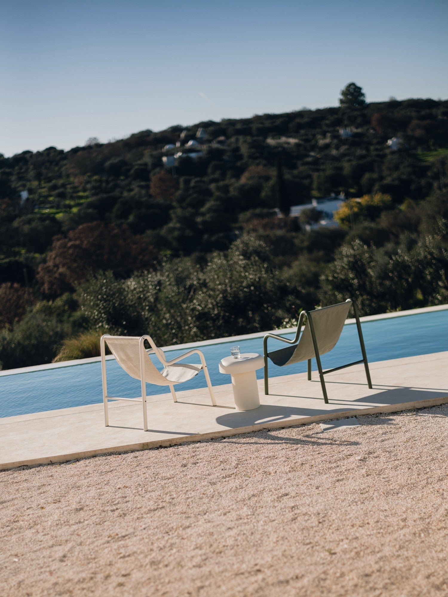 noo.ma Outdoor Miko Side Table, a cream-colored sculptural outdoor side table crafted from durable concrete with a smooth, matte finish. It features an organic, pebble-shaped top on a sturdy cylindrical base, embodying an organic modern and minimalist design. This contemporary outdoor accent table is perfect for poolside lounging, patio decor, or garden settings.