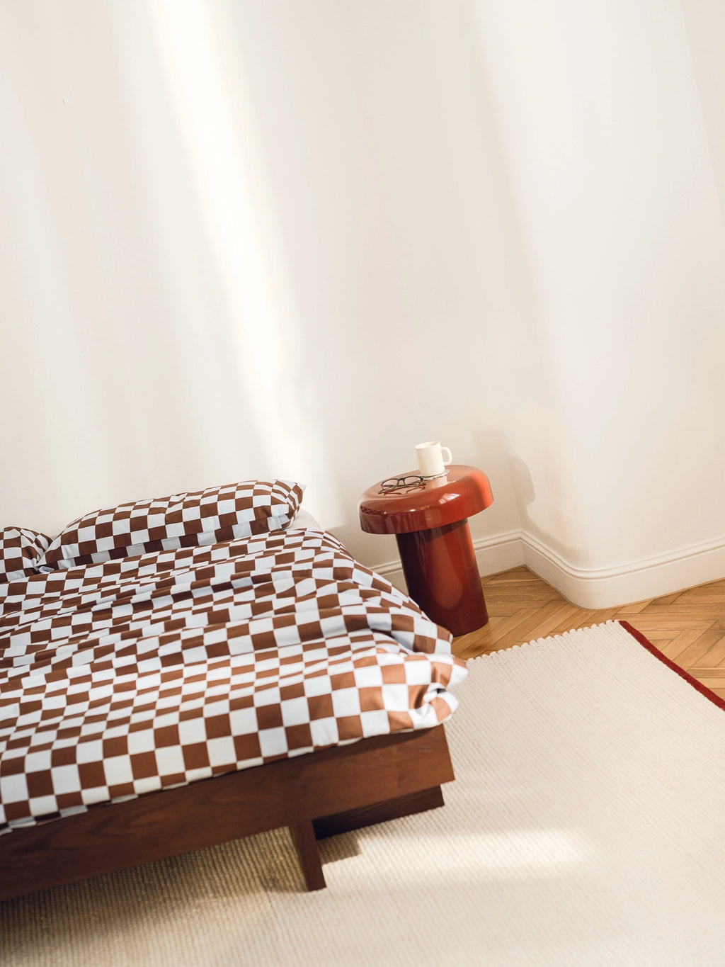 noo.ma Miko Side Table, a glossy burnt orange sculptural side table with a distinctive mushroom shape and smooth lacquered finish. This contemporary accent table features a round top and a sturdy cylindrical base, bringing an organic modern touch to any space. Perfect as a minimalist bedside table or a vibrant living room accent.