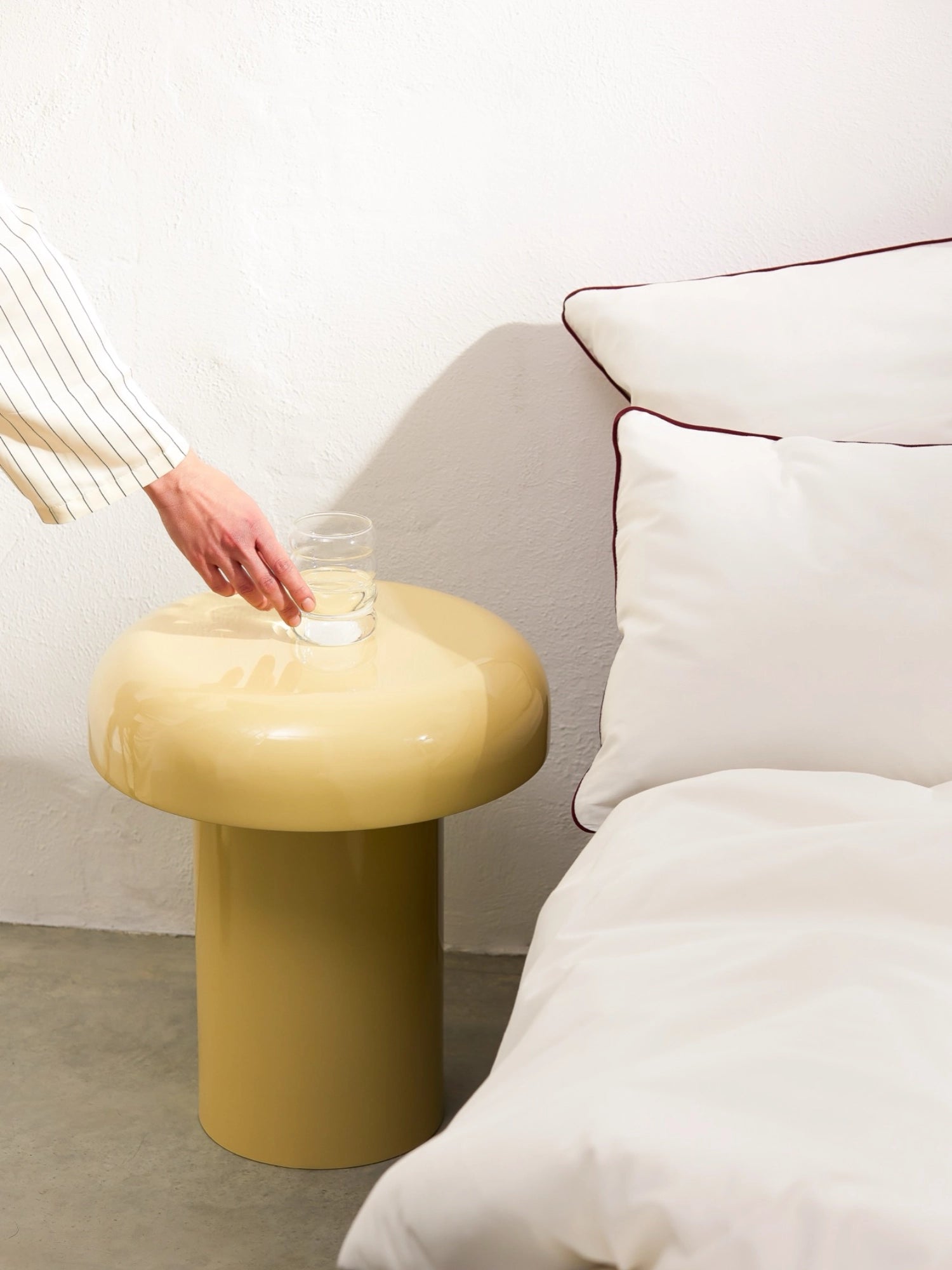 noo.ma Miko Side Table, a contemporary minimalist side table featuring a glossy pale mustard yellow lacquered finish and a distinctive mushroom-like sculptural shape with a round top and cylindrical base. This organic modern accent table is perfect as a stylish bedside table or for adding a playful touch to a living room.